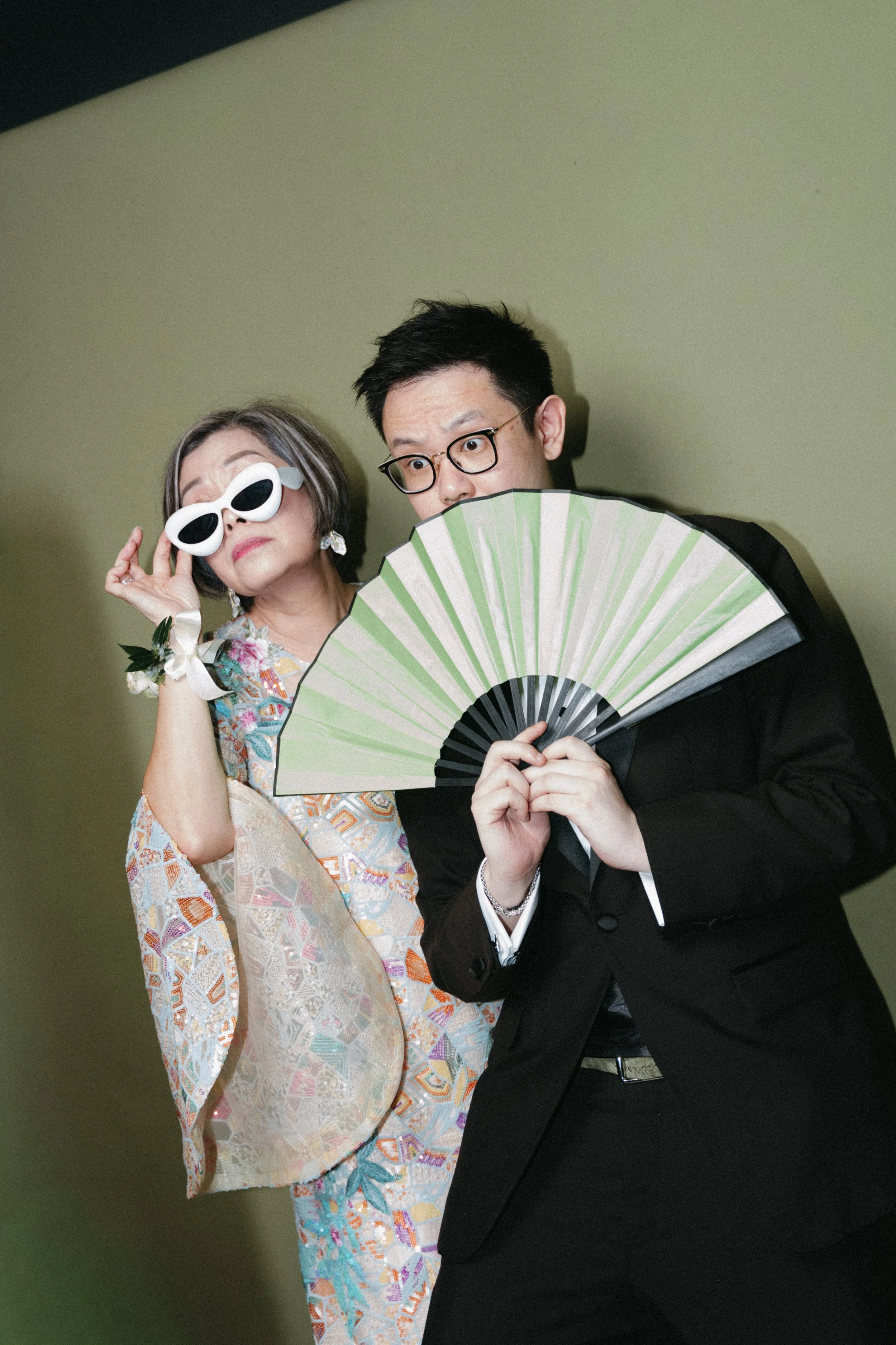 Guests posing with fan and sunglasses in photobooth at wedding reception party