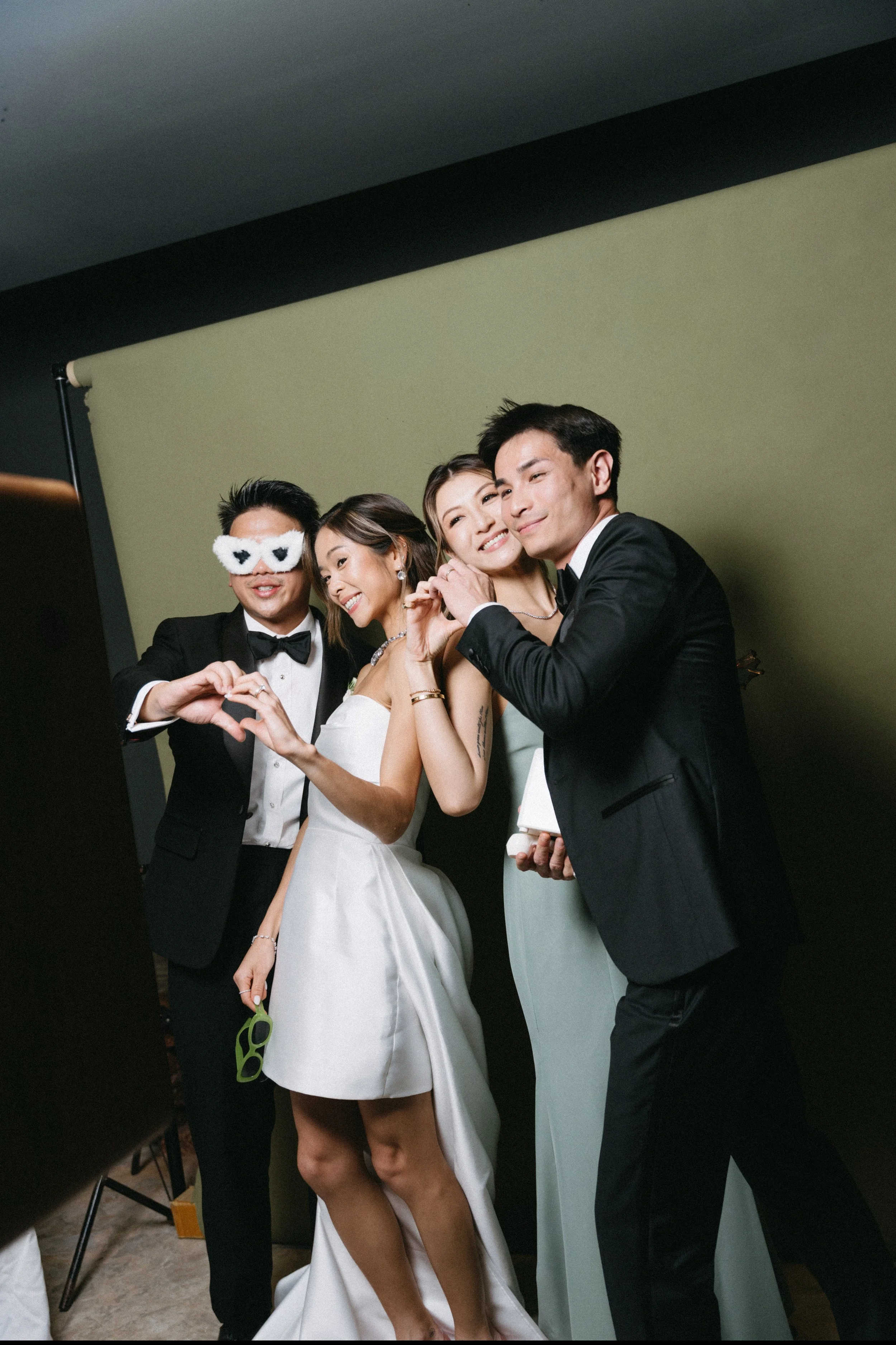 Bride and groom posing in photobooth with guest at wedding reception party