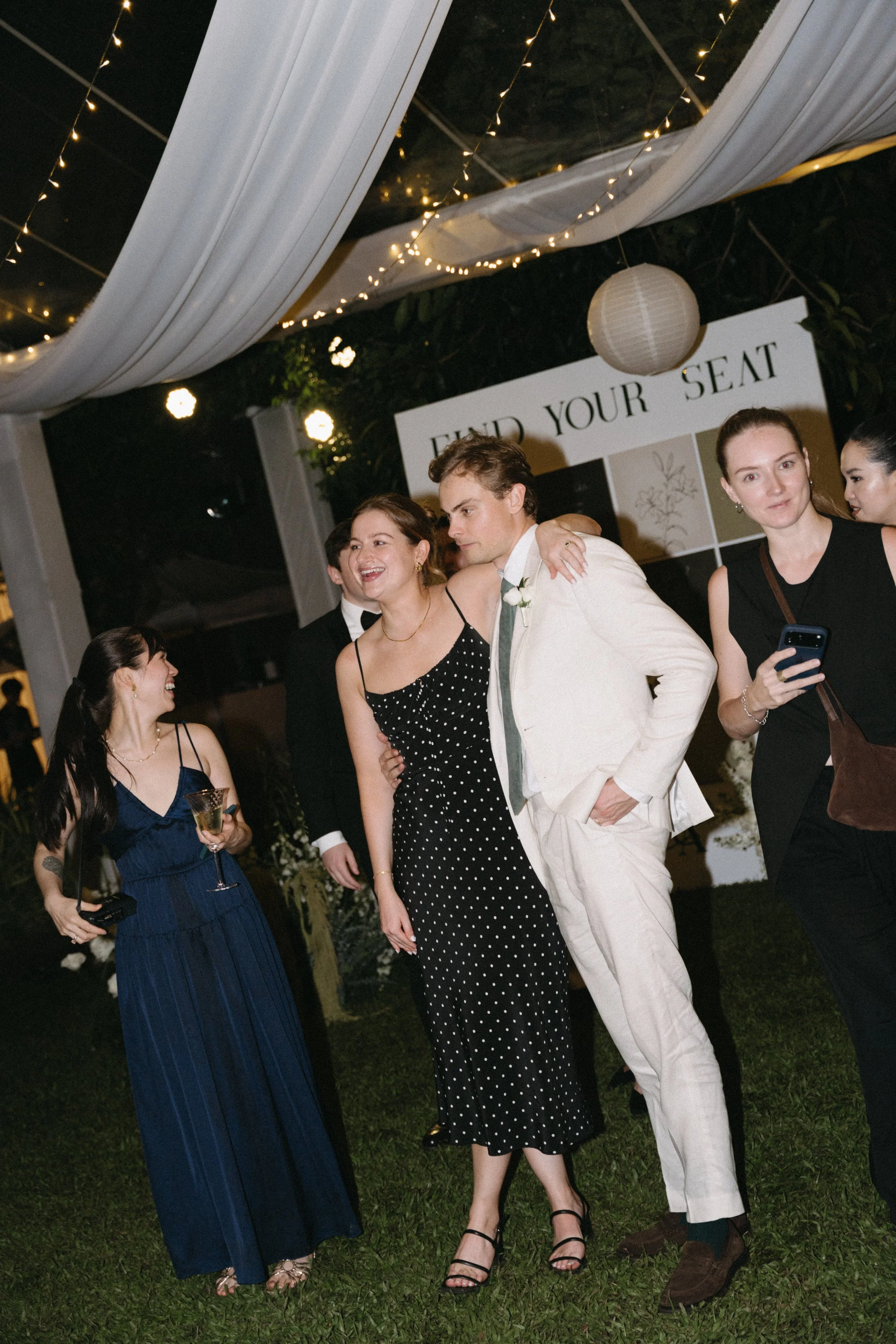 Guests standing together under fairy lights at COMO Point Yamu reception