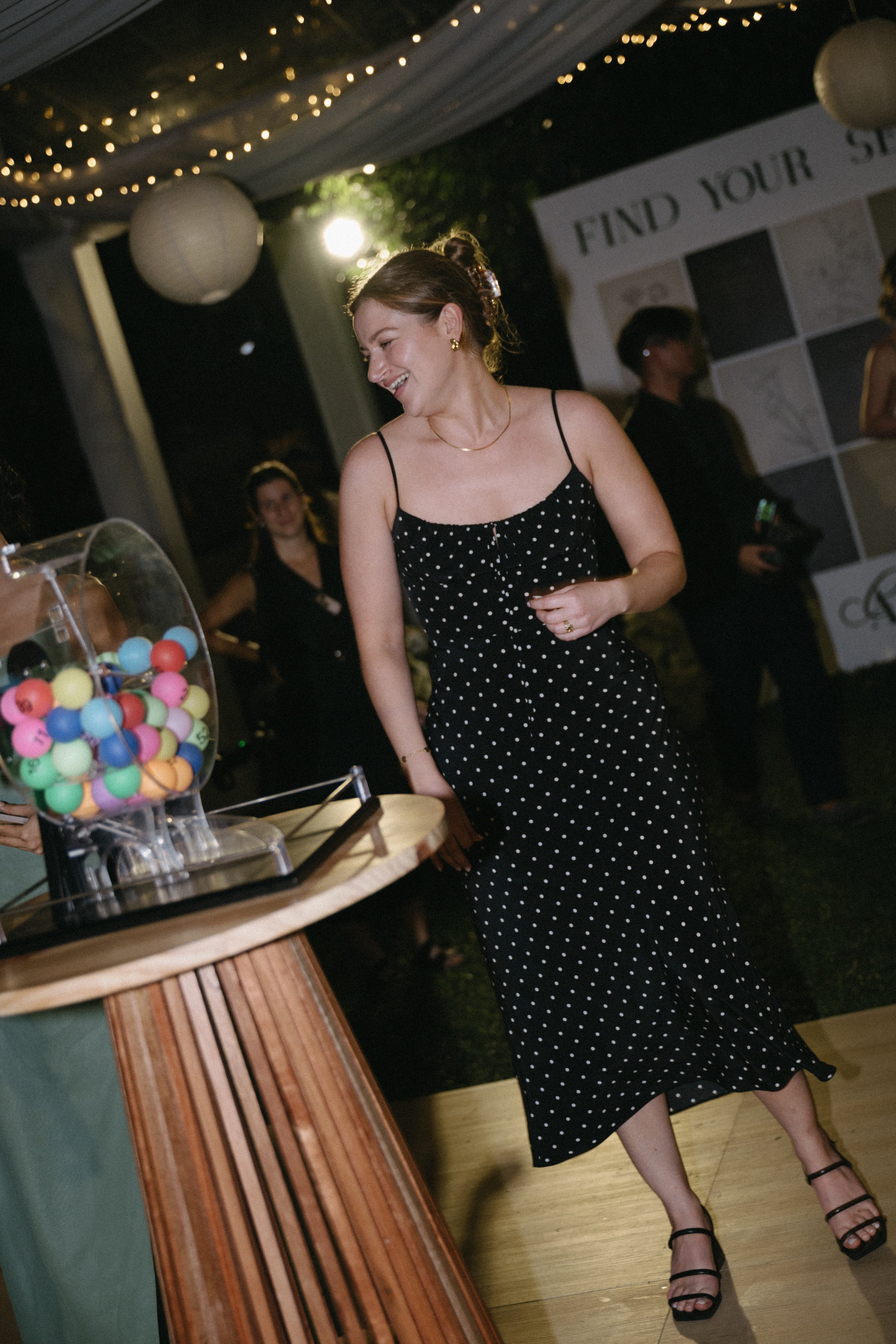 guest in polka dot dress standing next to colourful bingo machine during reception