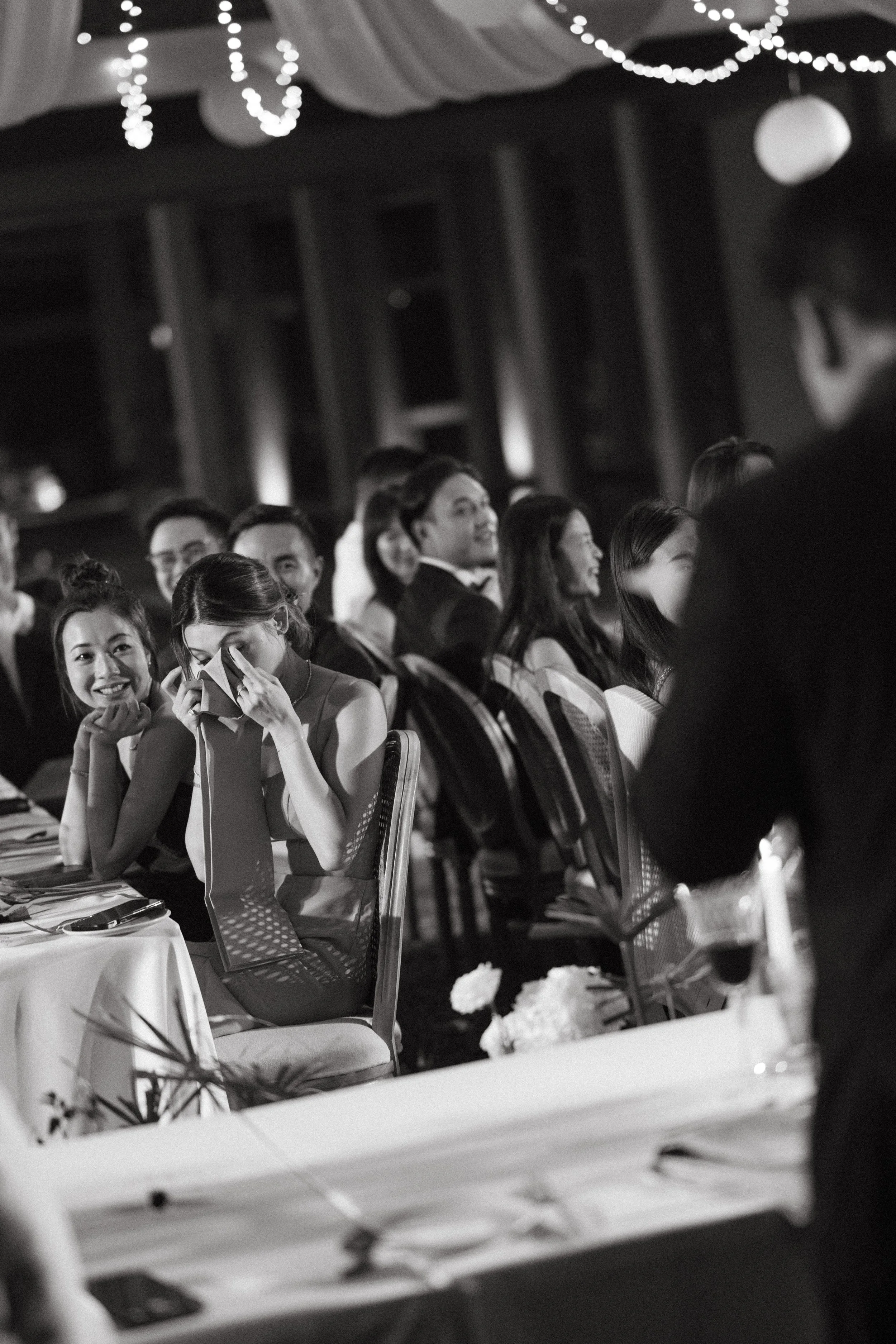 Wedding guests laughing together at reception table during speeches