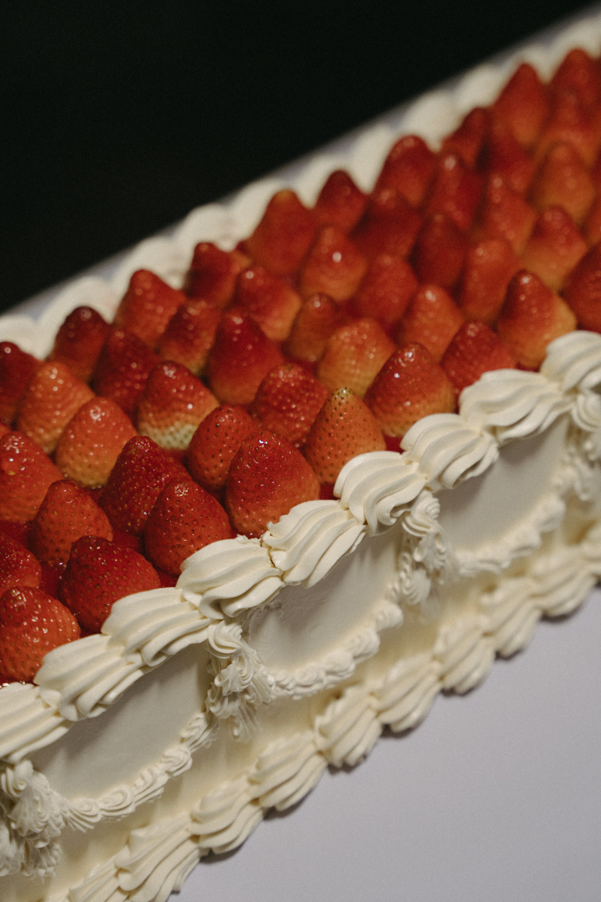 Close-up of fresh strawberries and piped cream on wedding cake, dessert detail shot