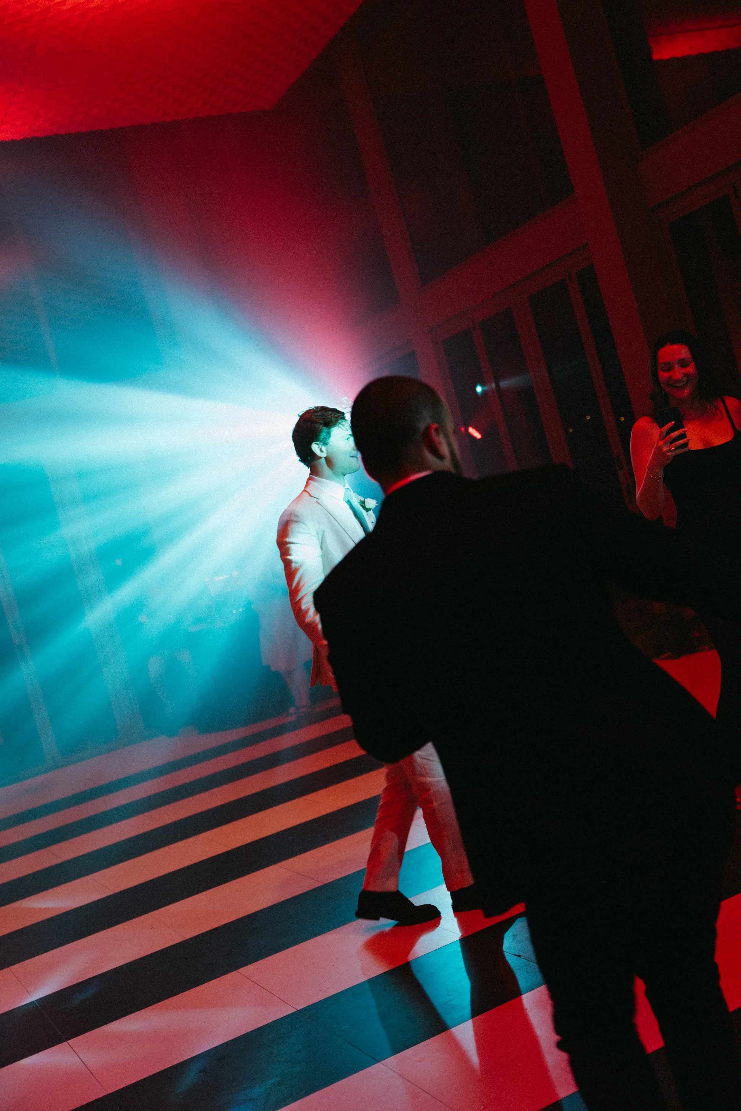 Guests dancing under red and blue lighting on striped dance floor