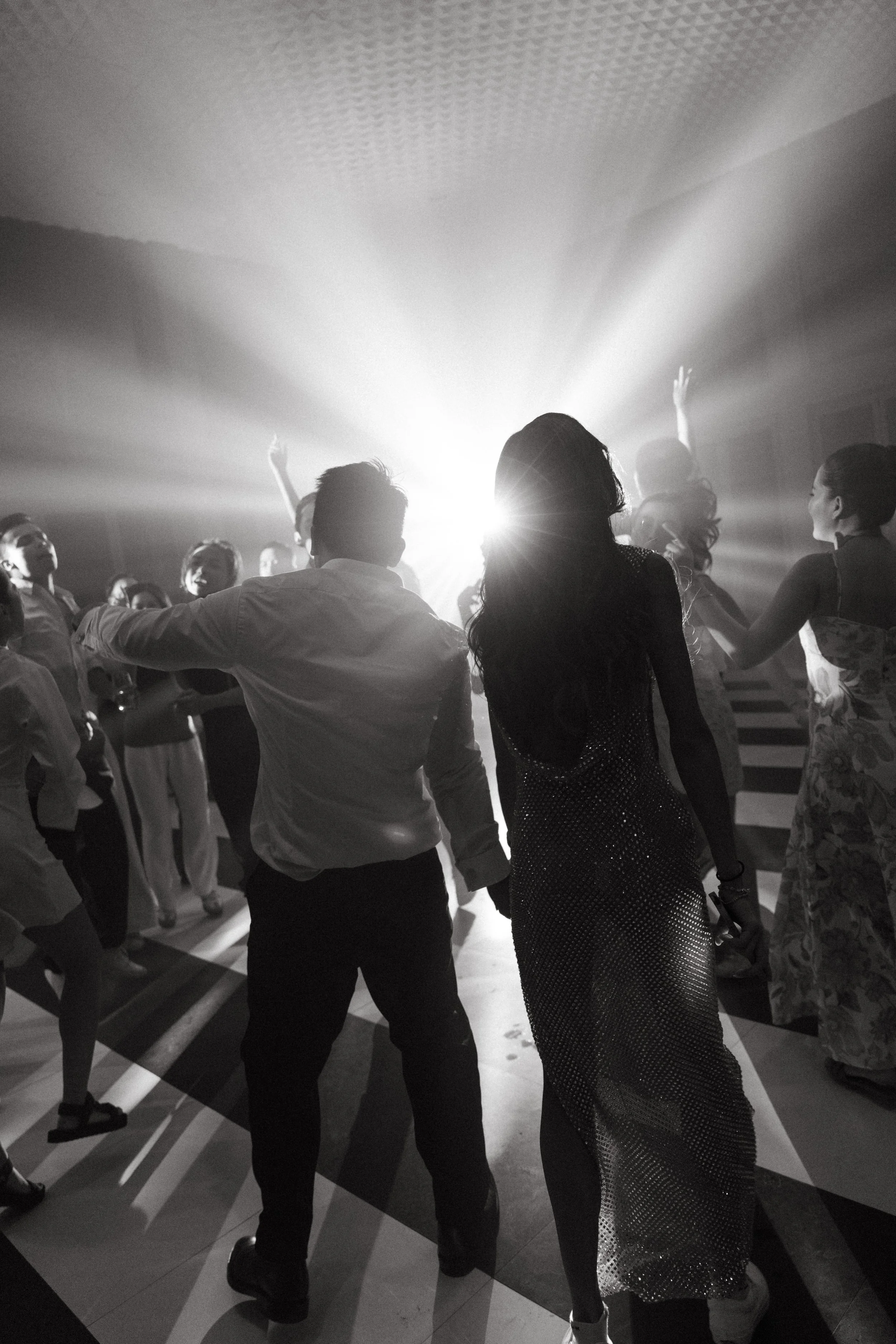 Guests silhouetted dancing together under dim reception lighting