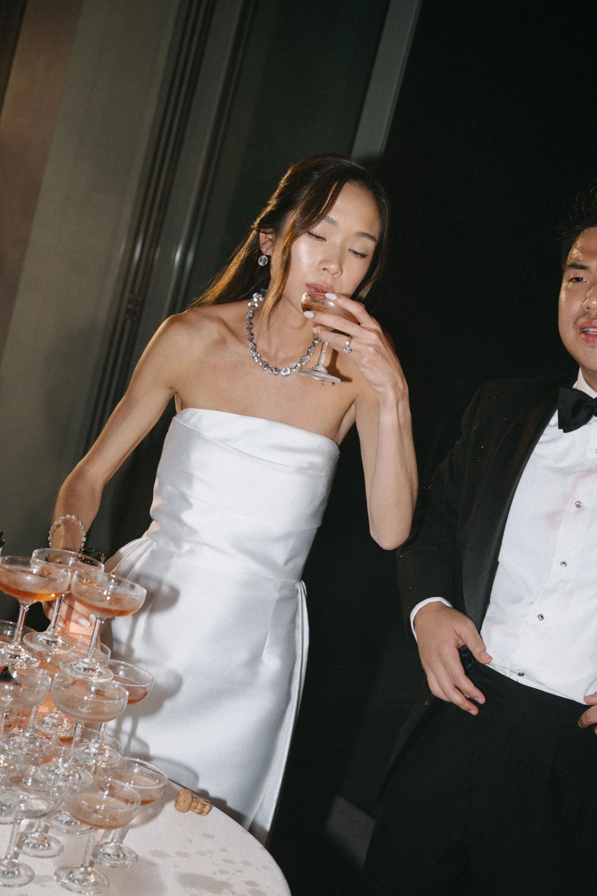 Bride sipping champagne in strapless gown at COMO Point Yamu reception