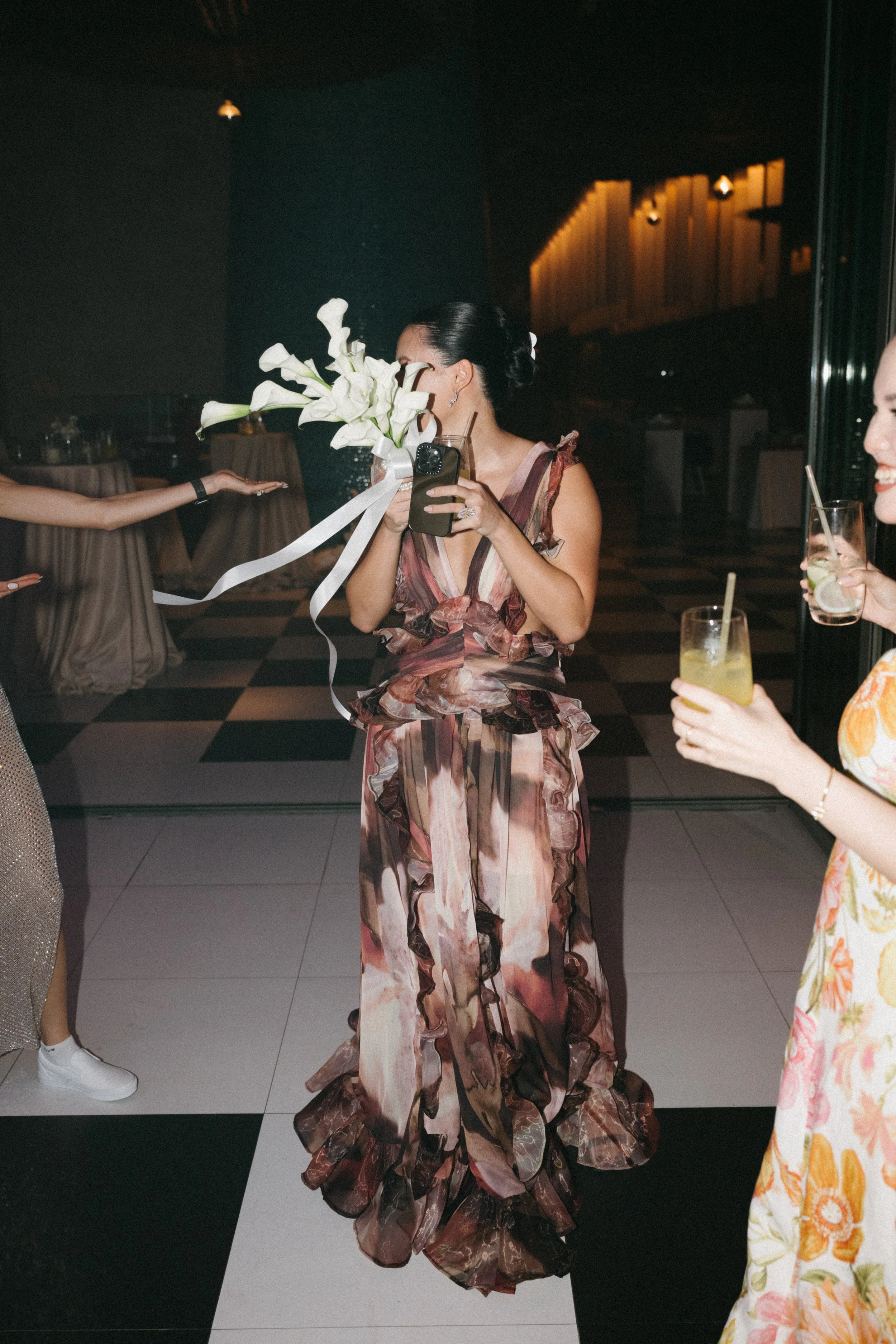 Guest holding bouquet while dancing at night reception celebration