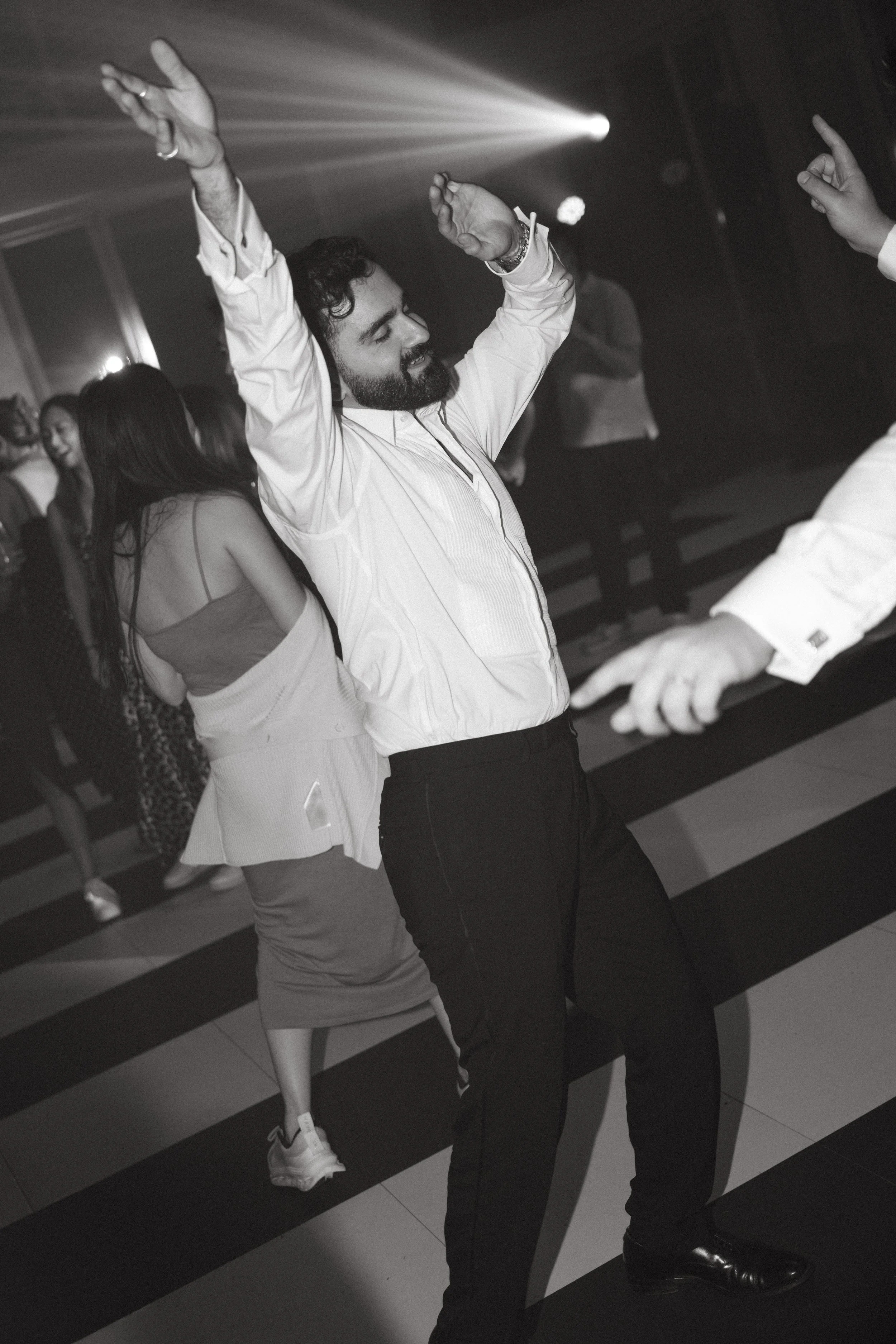 Guest dancing energetically with arms raised under party lights