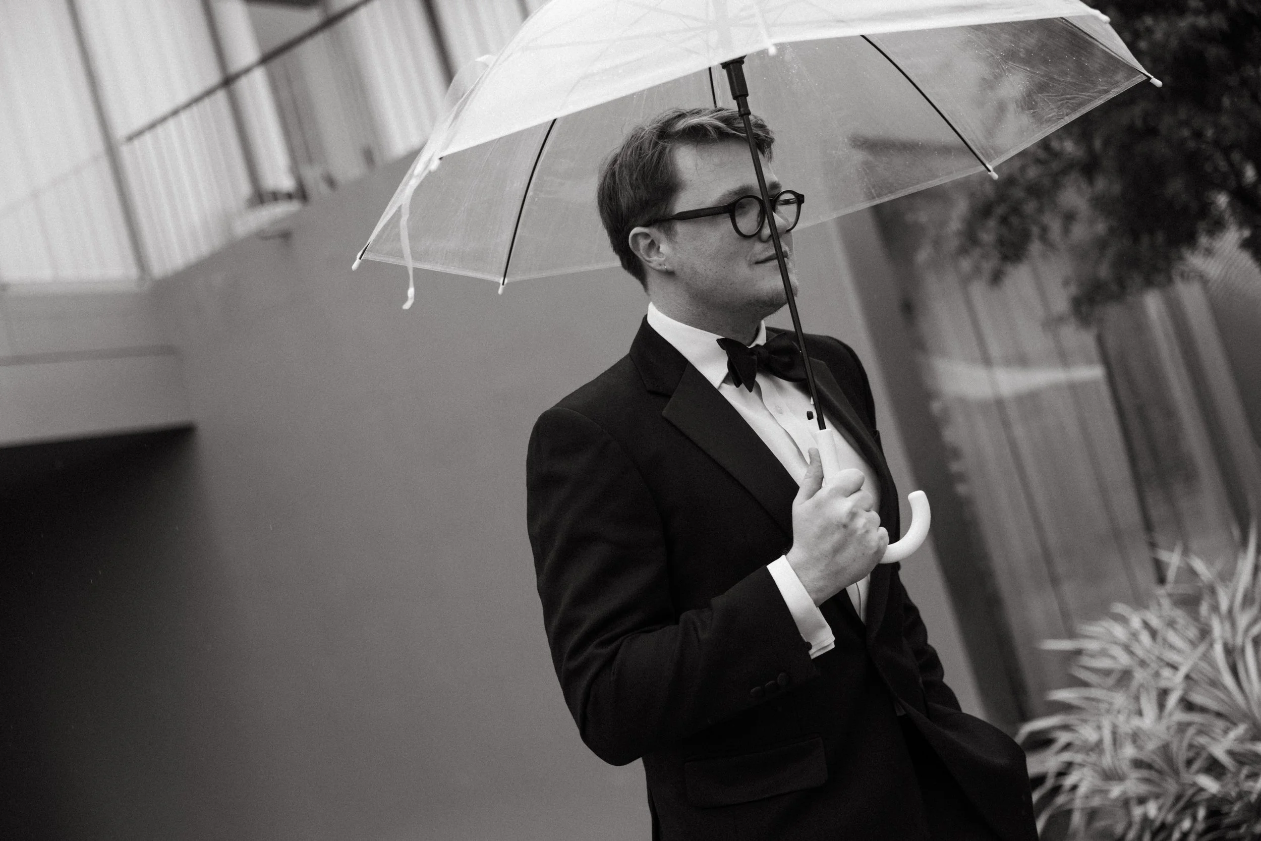 Guest in black tie holding a clear umbrella, editorial black and white portrait at COMO Point Yamu