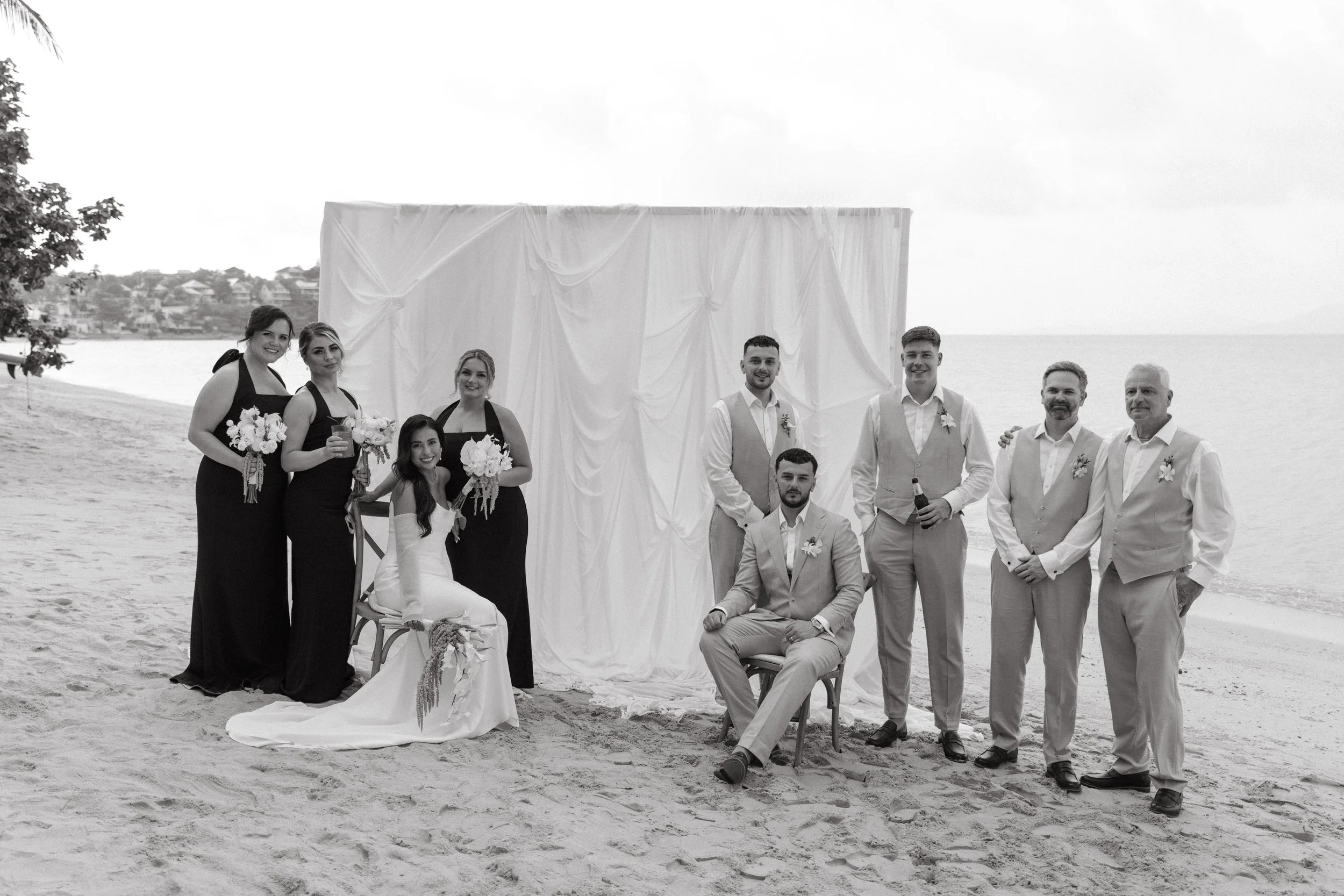 elegant portrait of bride and groom with entire wedding party on the beach after destination wedding ceremony
