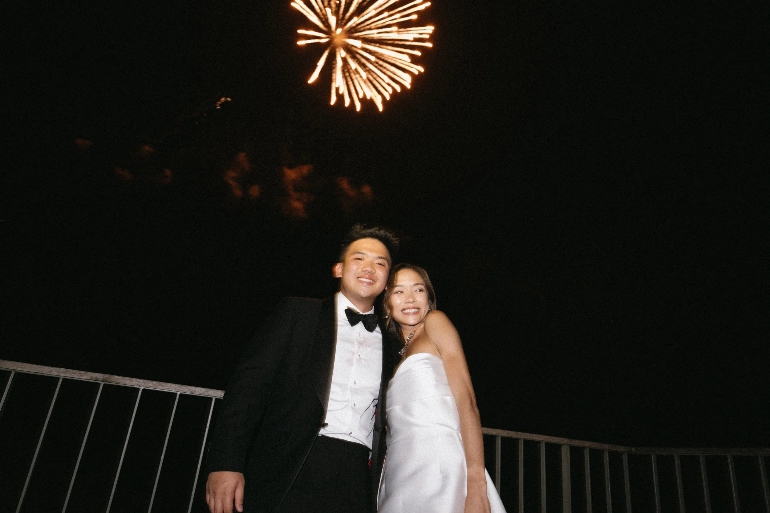 candid shot of bride and groom standing underneath fireworks during outdoor wedding reception