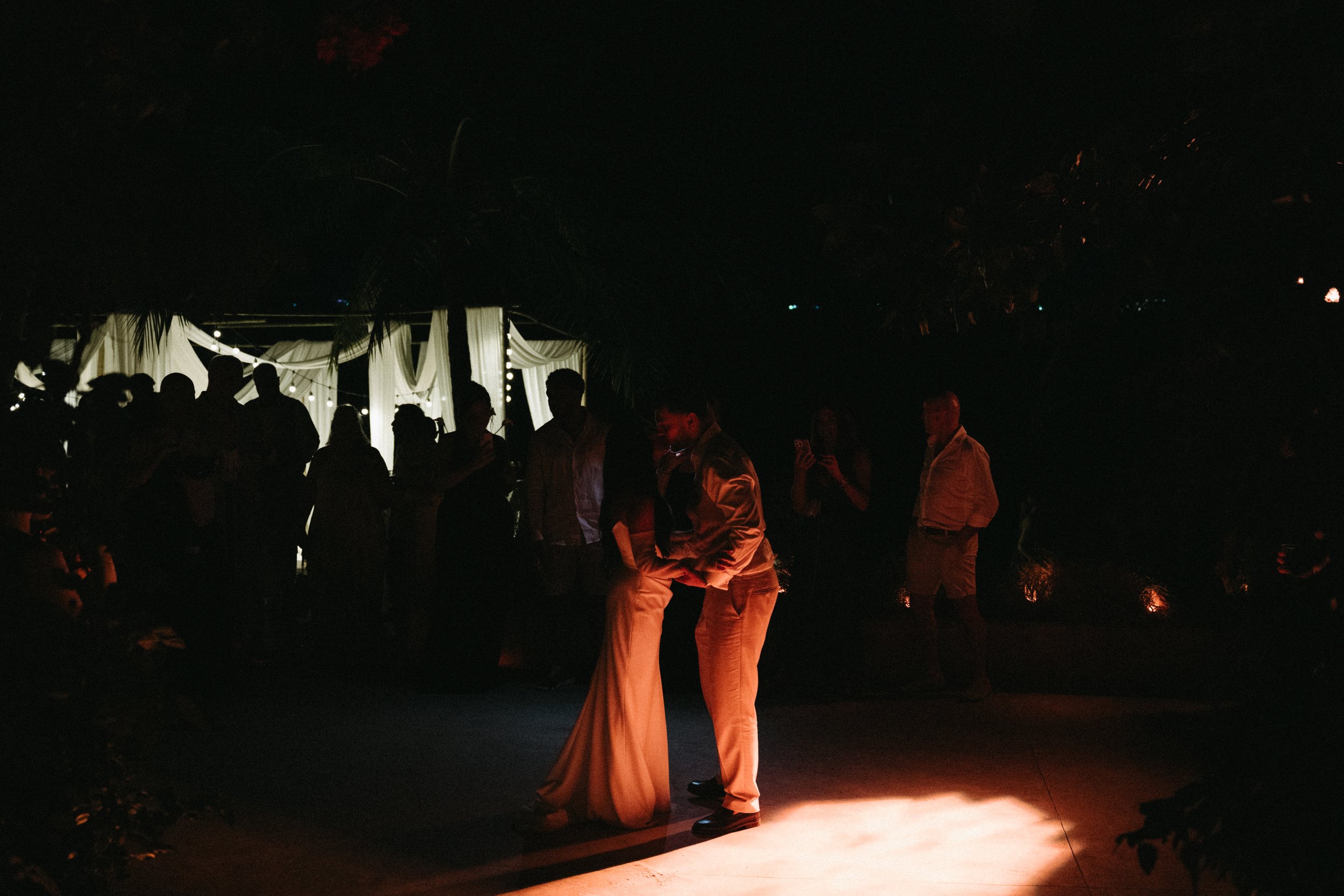 Bride and groom sharing their first dance under warm lighting at an outdoor beach wedding reception on Bangrak Beach, Odyssey Mansion, Koh Samui