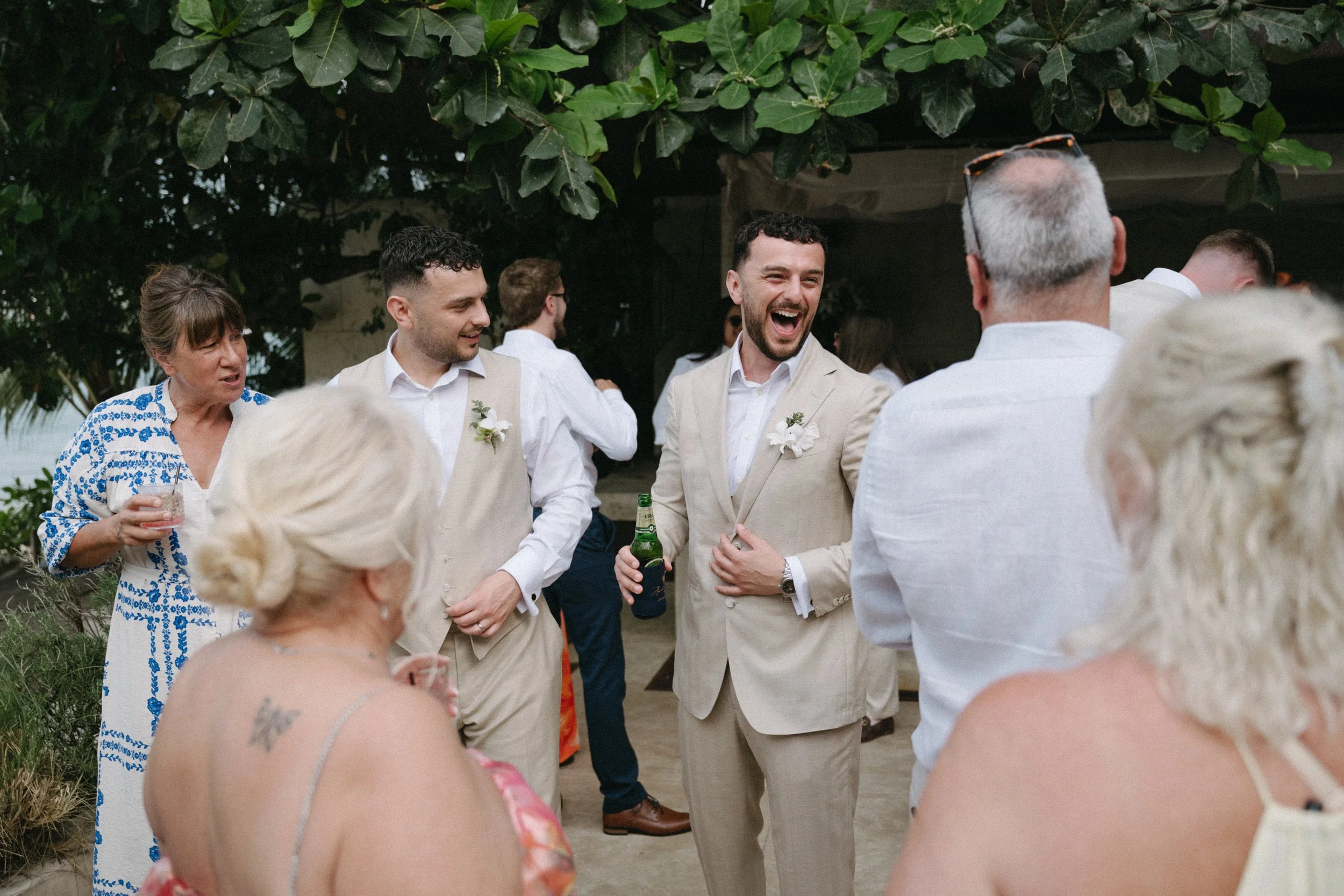 candid shot of groom laughing with wedding guests during welcome drinks before the ceremony begins