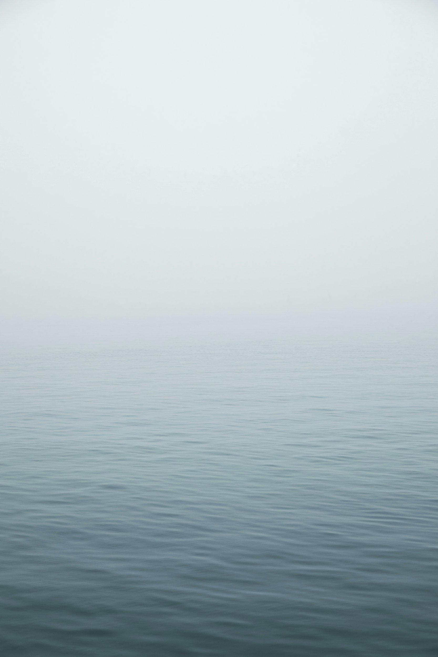 Calm, foggy ocean horizon with light ripples.