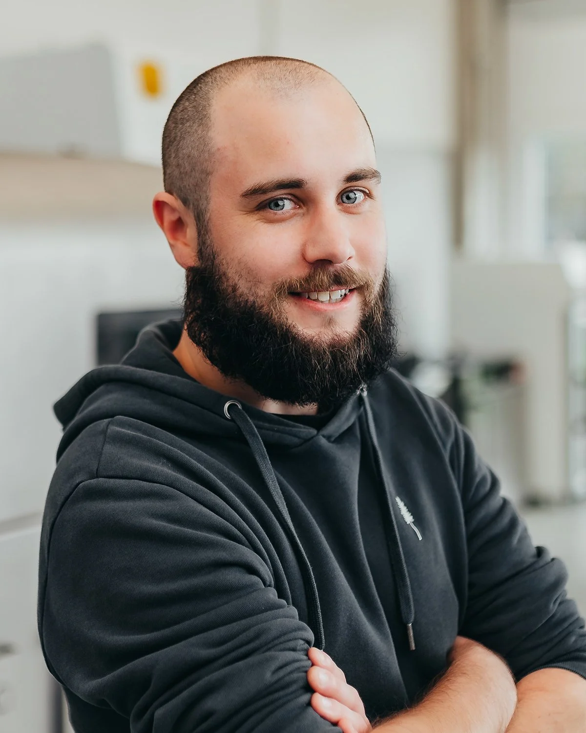 Smiling man with a beard wearing a hoodie.