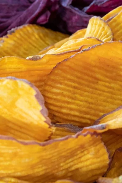 Close-up of ridged yellow and purple sweet potato chips.