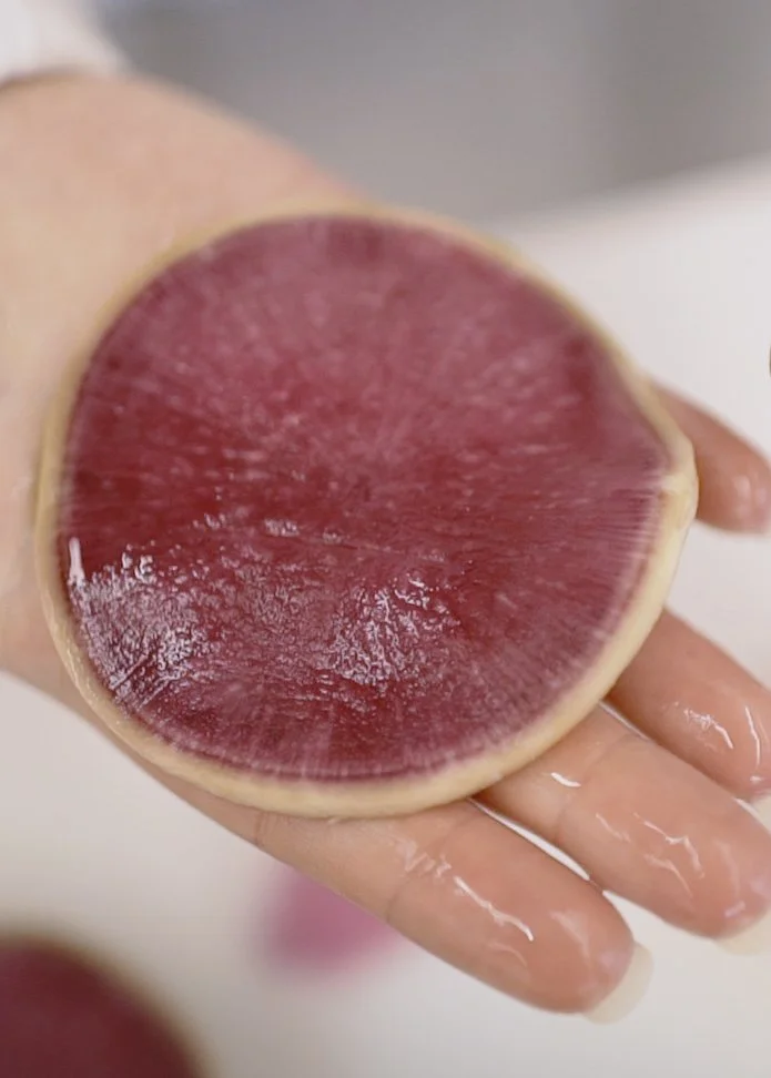 A sliced piece of beet on a hand