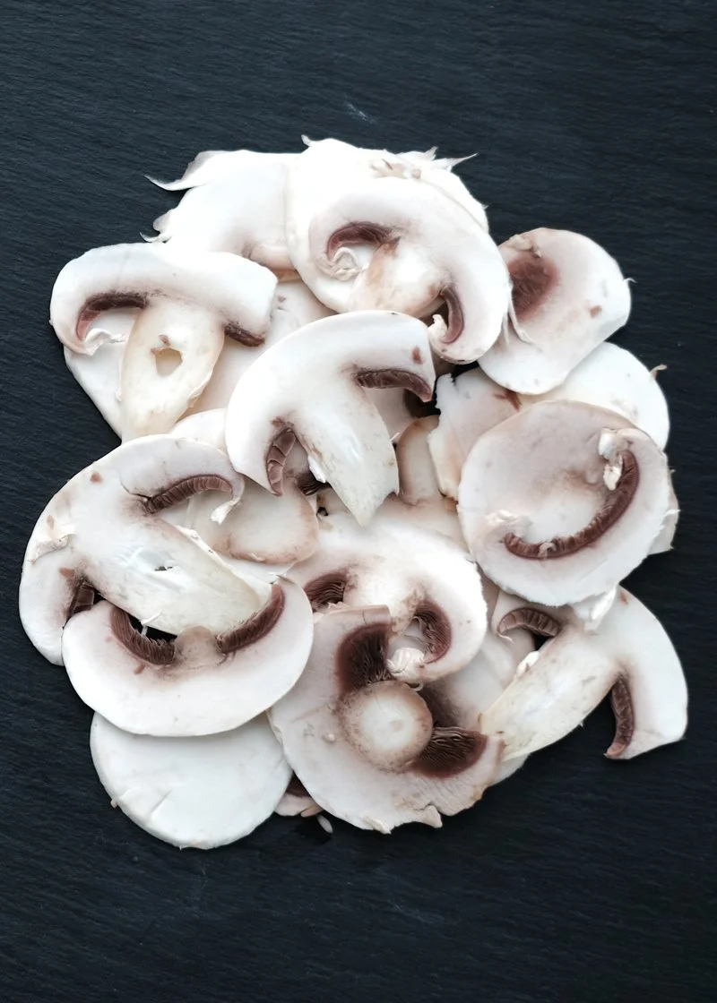 Sliced white mushrooms on a dark surface