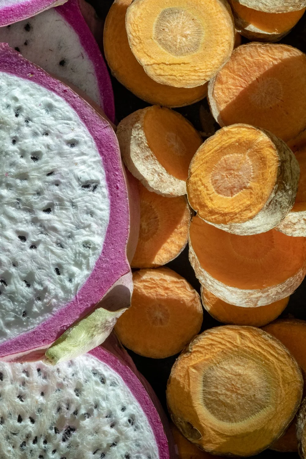 Close-up of sliced dragon fruit and carrot slices placed together.