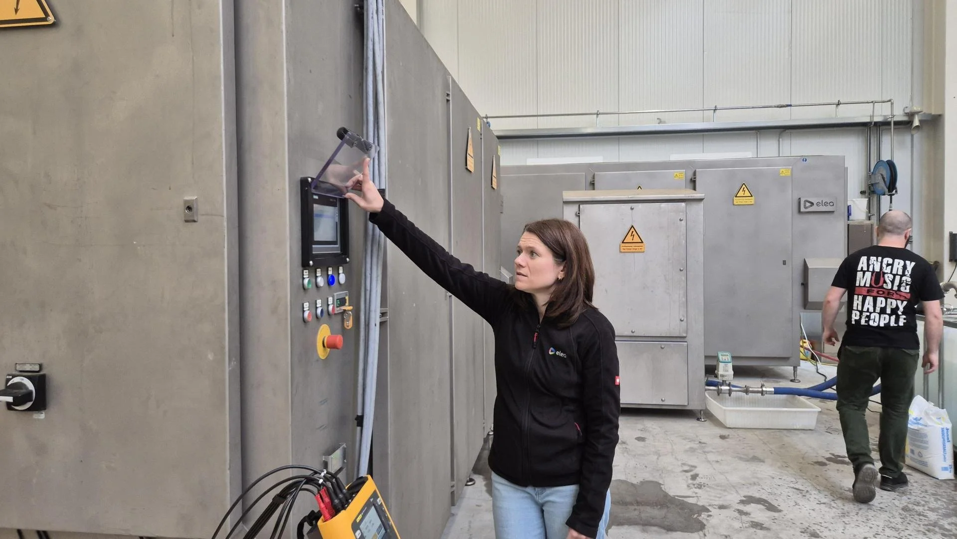 Four people standing in an industrial setting, discussing near large machinery.
