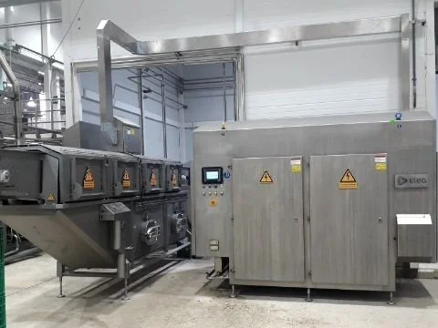Industrial food processing equipment in a factory, including stainless steel machinery with warning signs.
