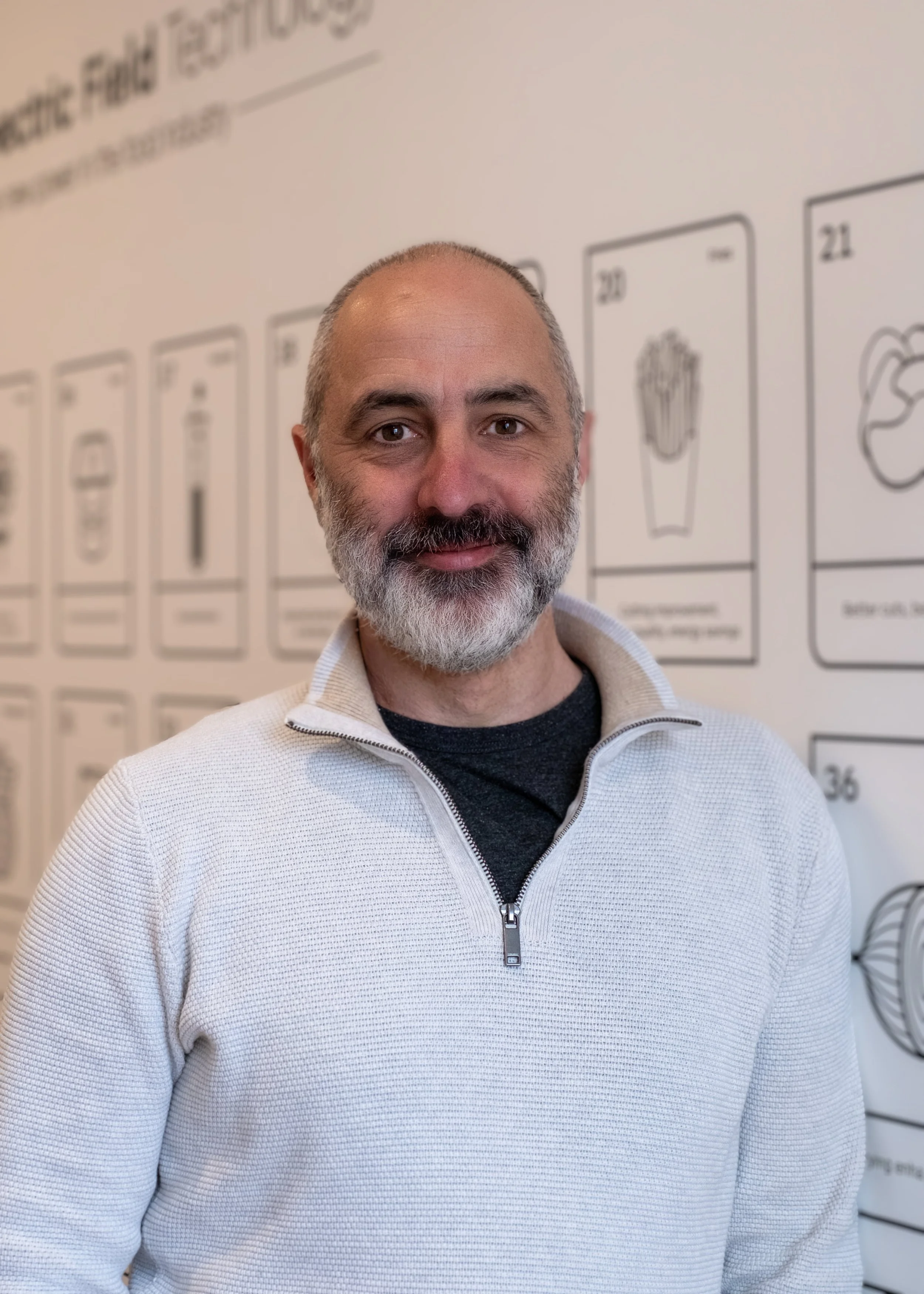 Man wearing sunglasses and a cap, standing in front of tall grass, black and white photo.