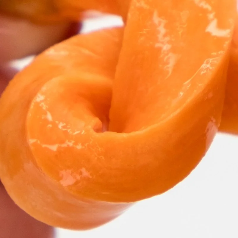 Close-up of orange sweet potato slice being stretched and twisted.