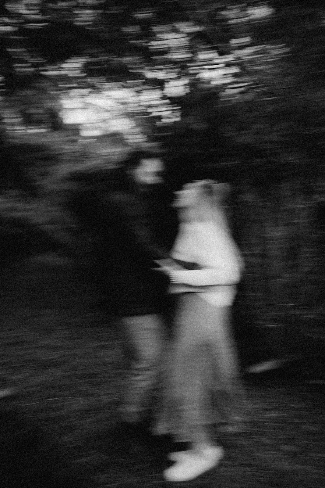 Blurry black and white photo of two people standing outdoors.