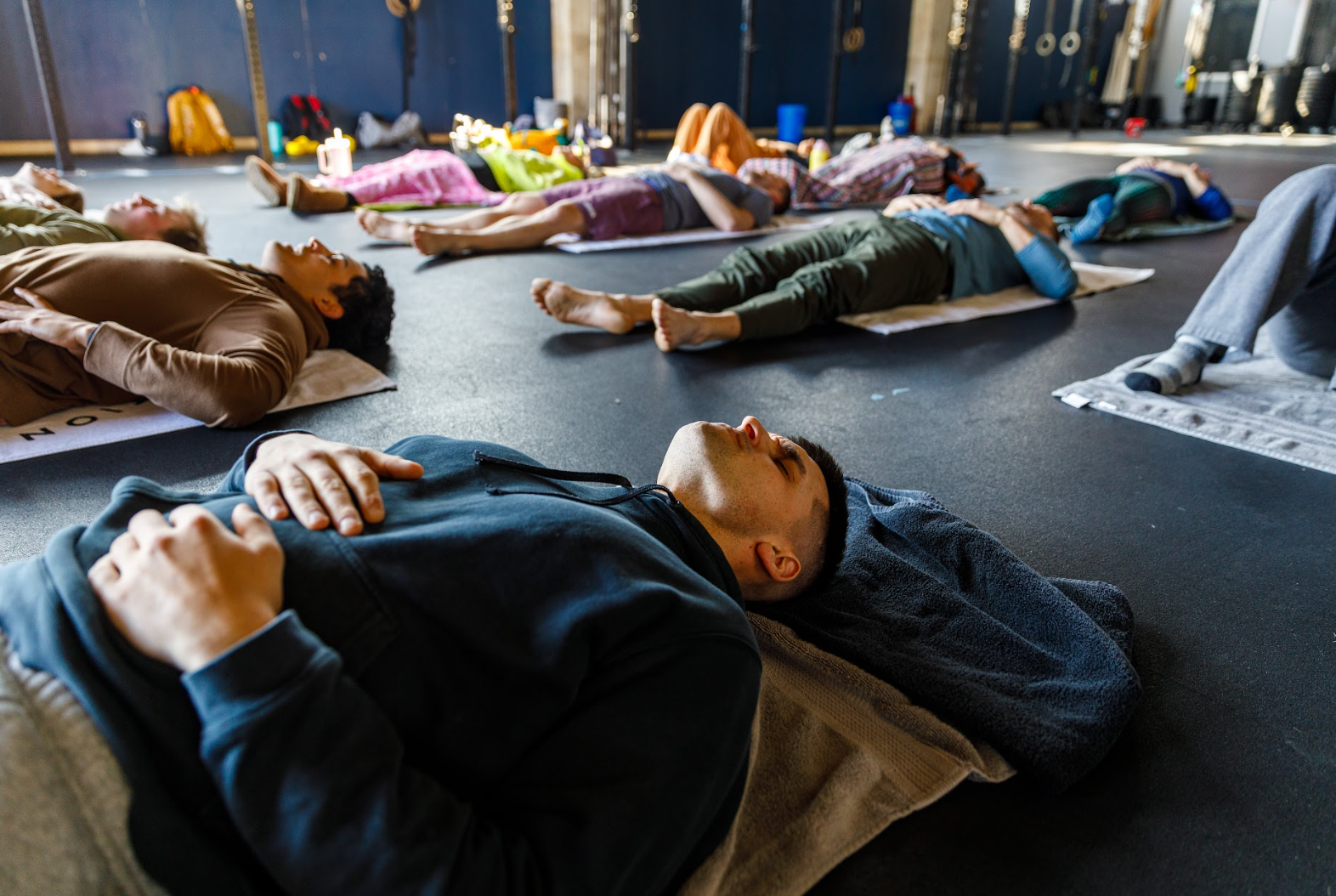 People lying on exercise mats in a gym, participating in a relaxation or meditation class. Wellness Membership St. Louis | Breath & Exposure STL