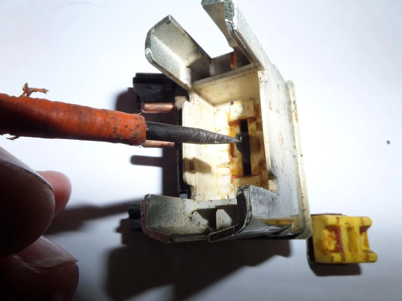 A person using a screwdriver to work on an electrical relay switch.
