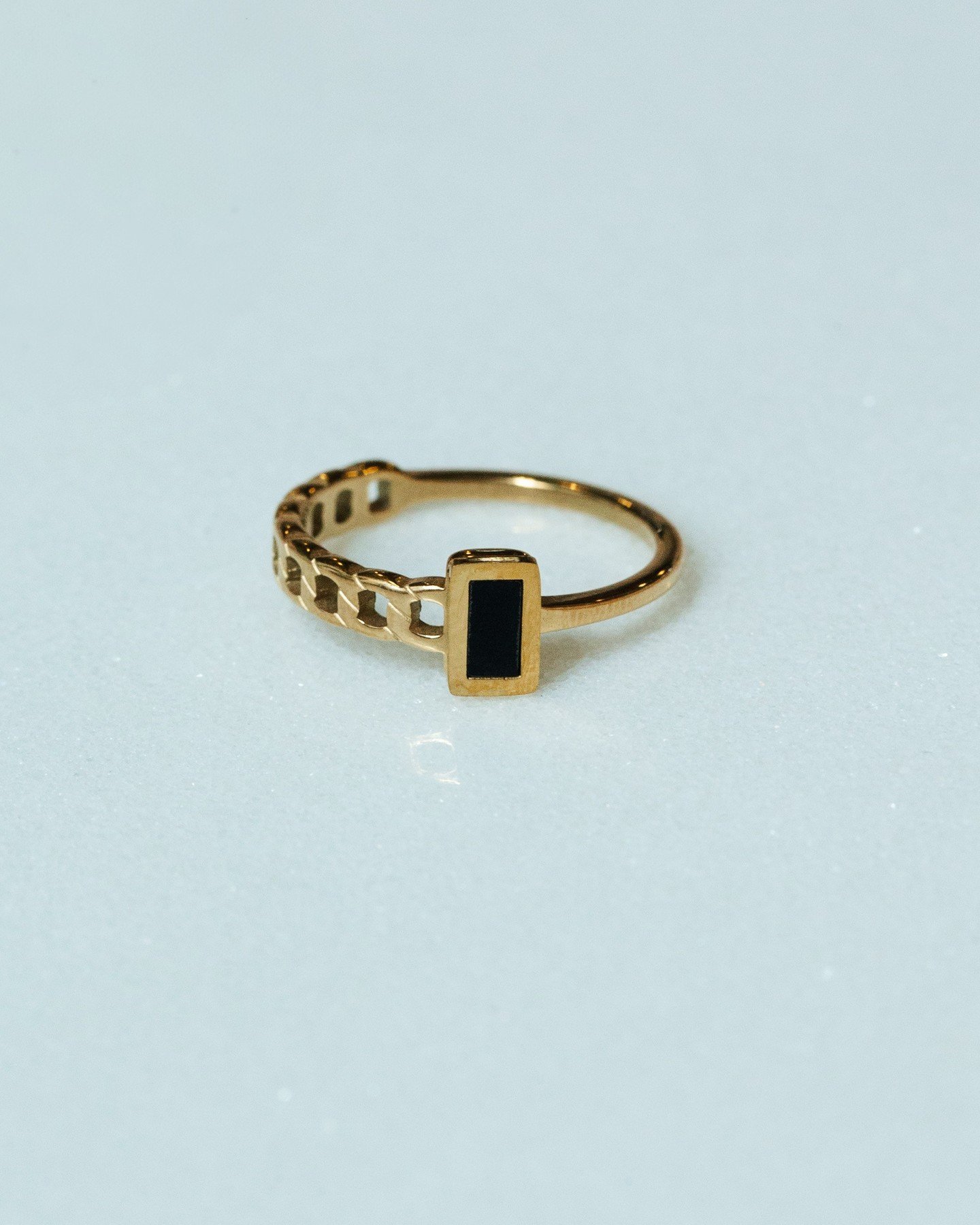 Not your average ring. The Mania Ring takes its name from the Greek goddess of madness and frenzy&mdash;fitting for a piece this bold. Gold chain-link, jet-black inlay, waterproof, and made to turn heads.