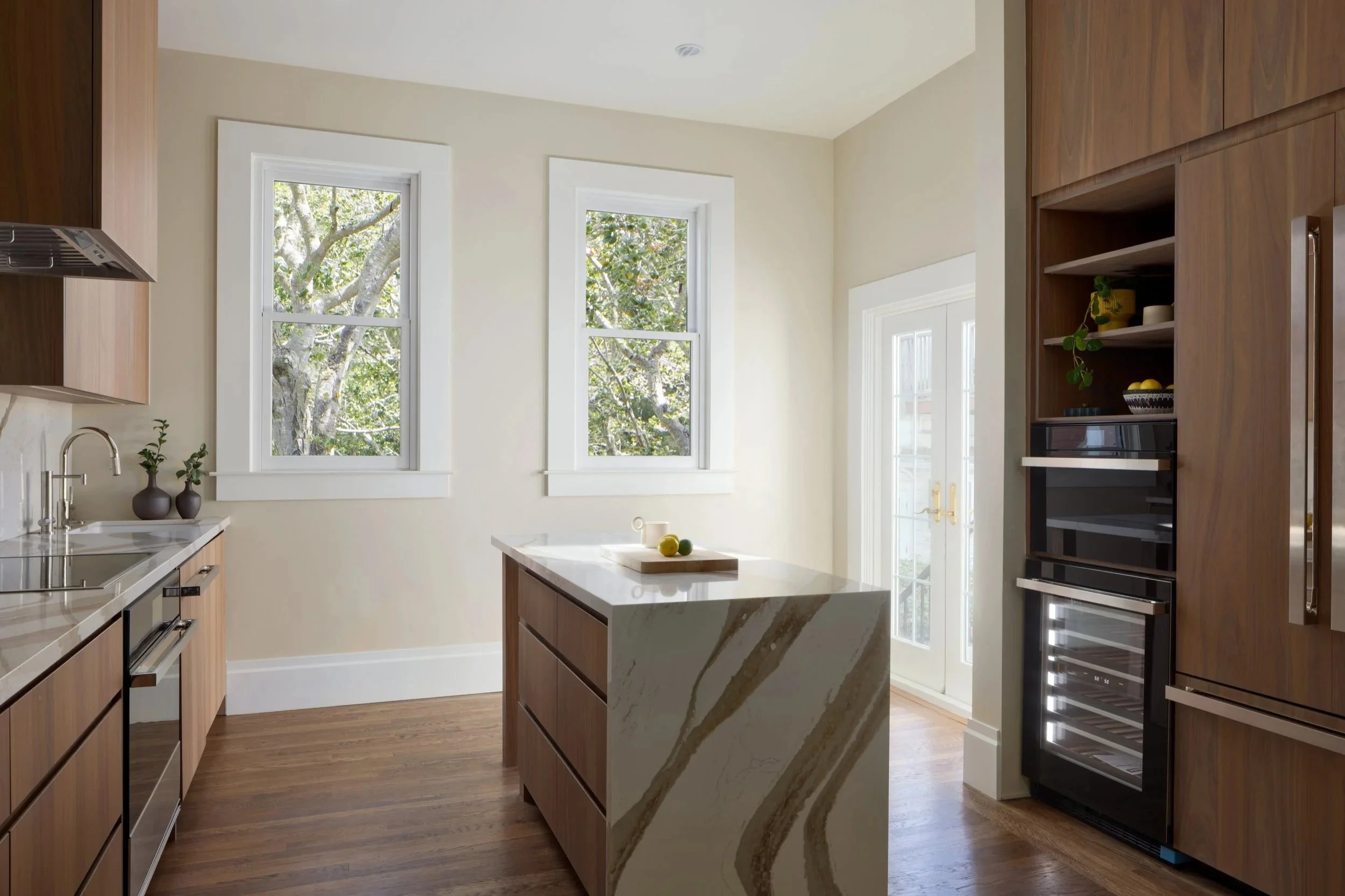 Modern walnut kitchen renovation featuring full-height wood cabinetry, waterfall quartz island, integrated appliances, and natural light in a san francisco residential remodel by From David Designs.