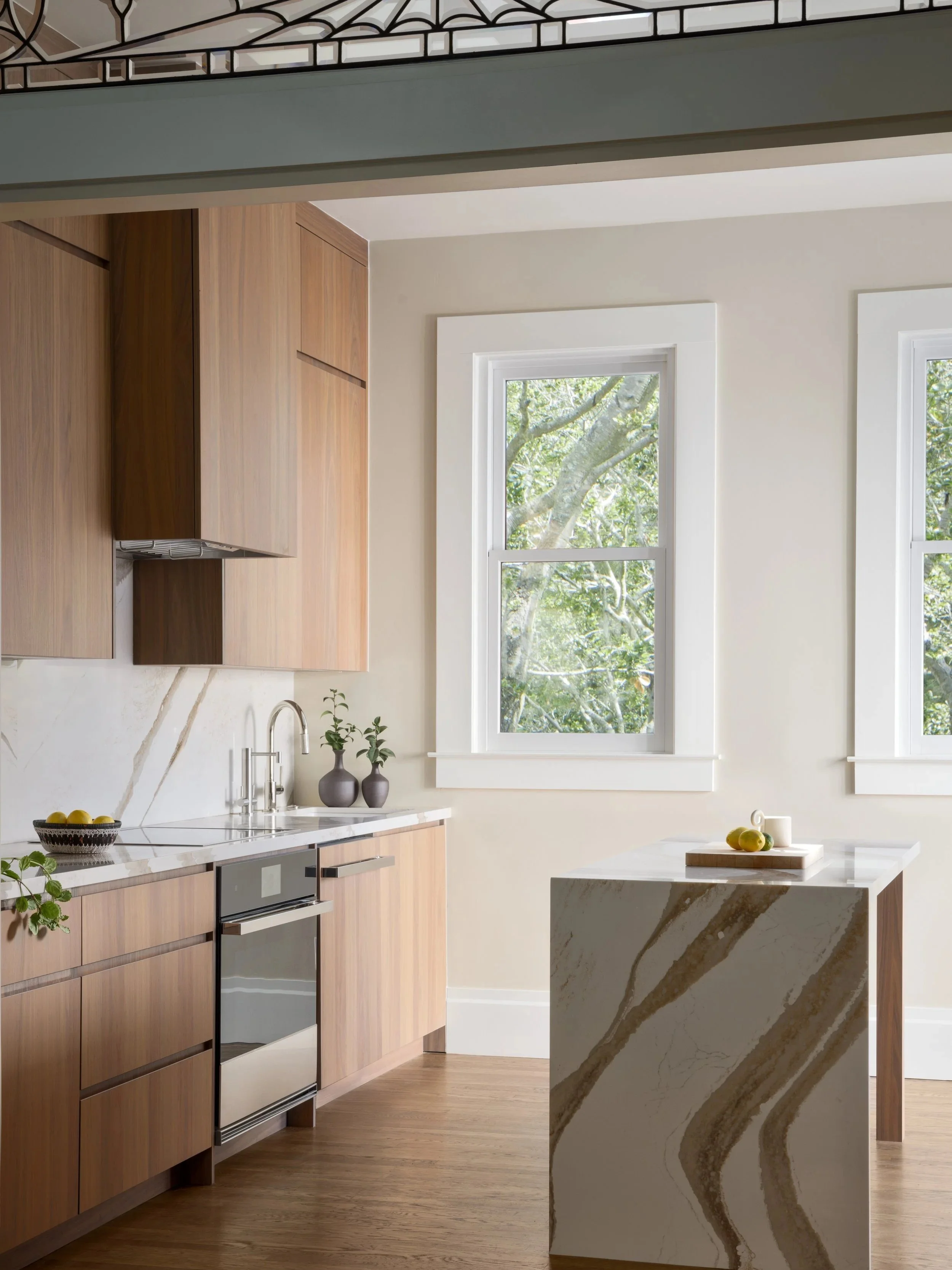 Modern walnut kitchen renovation featuring full-height wood cabinetry, waterfall quartz island, integrated appliances, and natural light in a san francisco residential remodel by From David Designs.