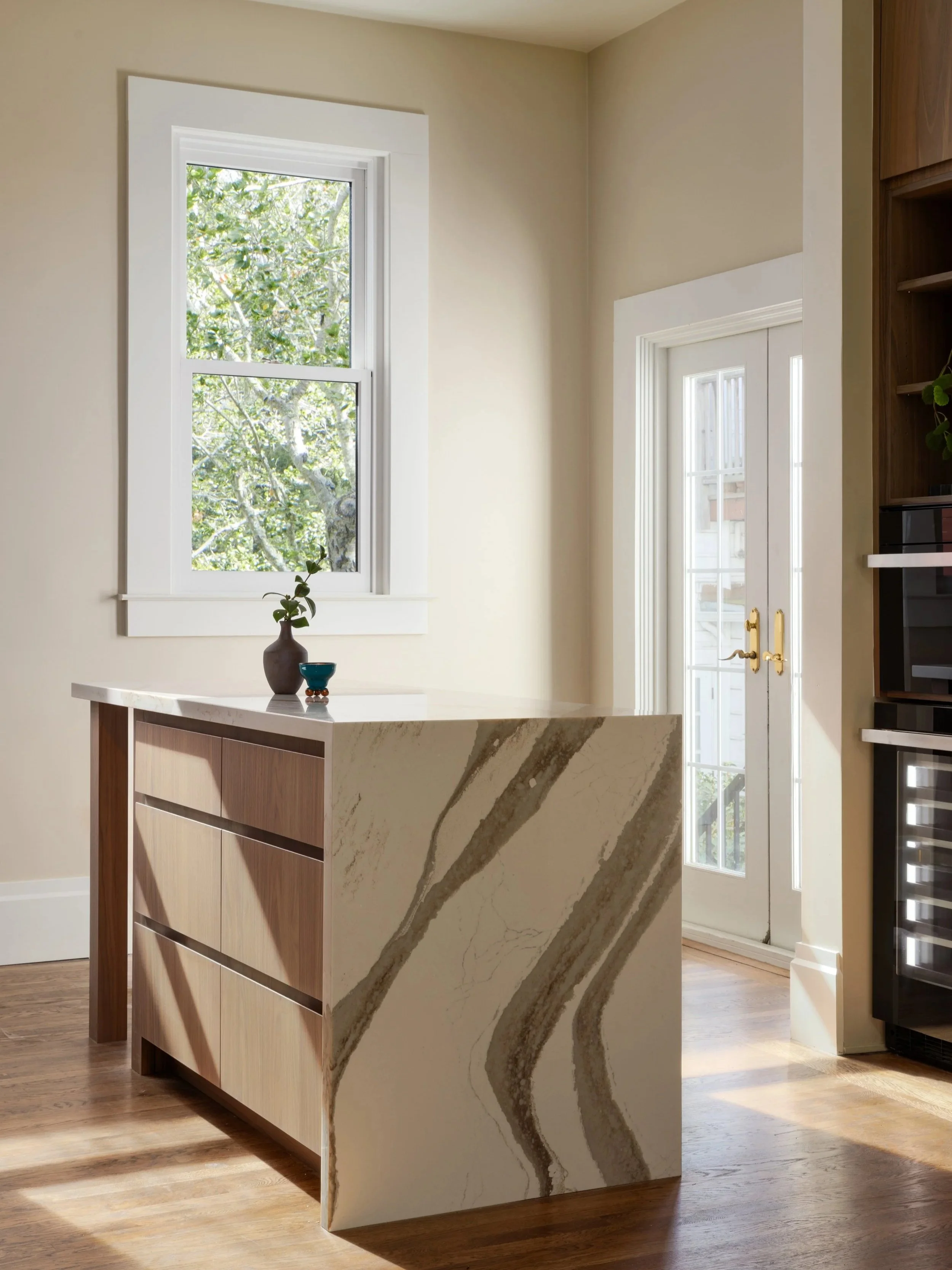 Modern walnut kitchen renovation featuring full-height wood cabinetry, waterfall quartz island, integrated appliances, and natural light in a san francisco residential remodel by From David Designs.