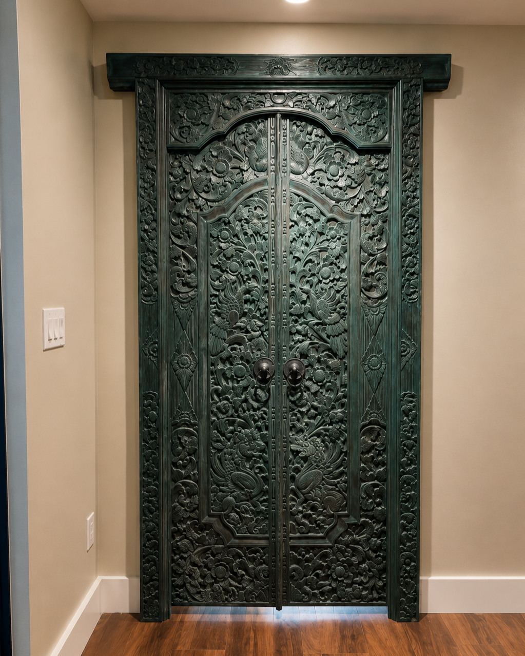 An imported Balinese carved wood door serves as a focal point within this custom library renovation, introducing craftsmanship, texture, and cultural character to the interior architecture.