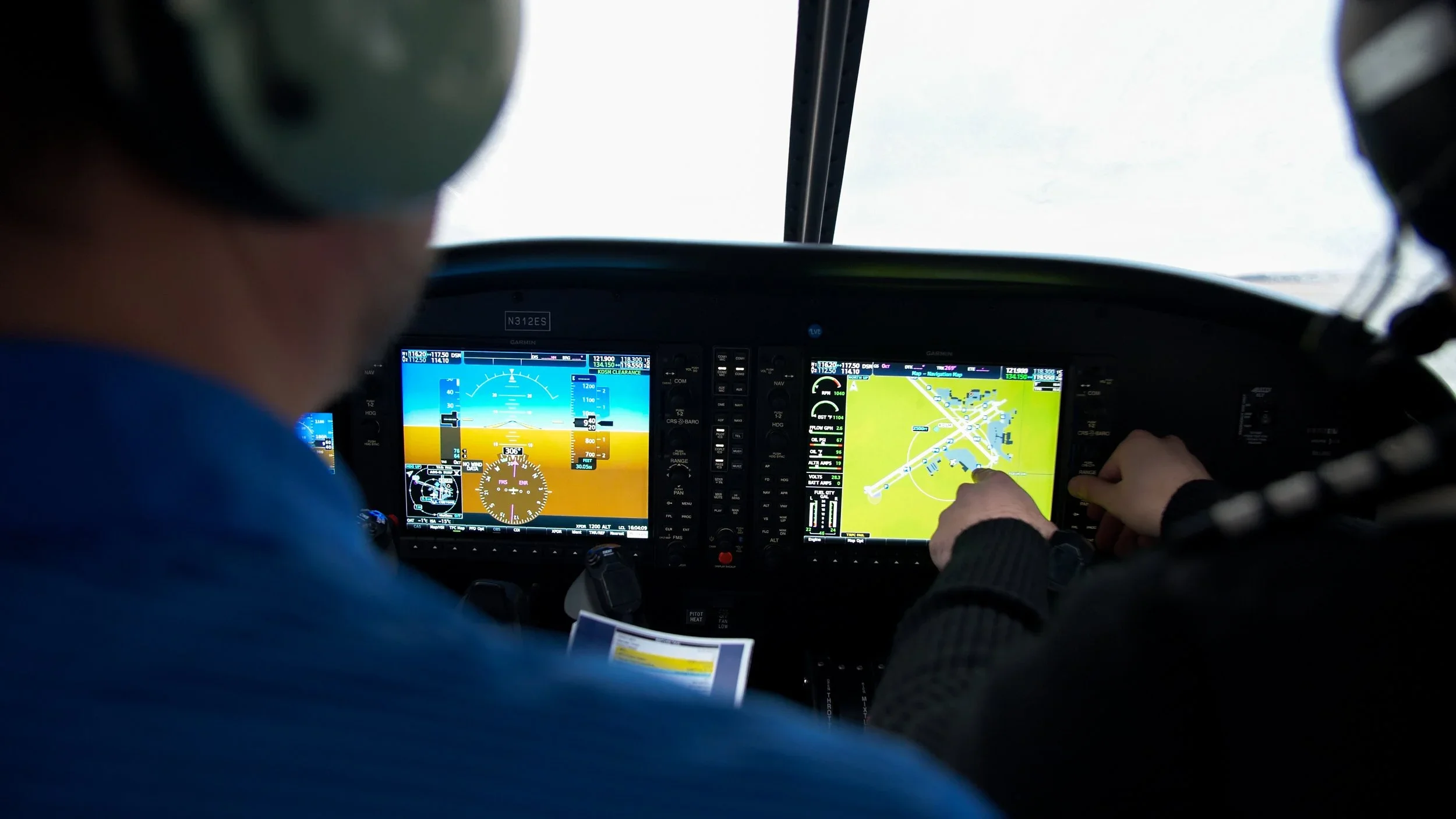 Photo of a pilot looking at cockpit navigation screens while flying an aircraft.