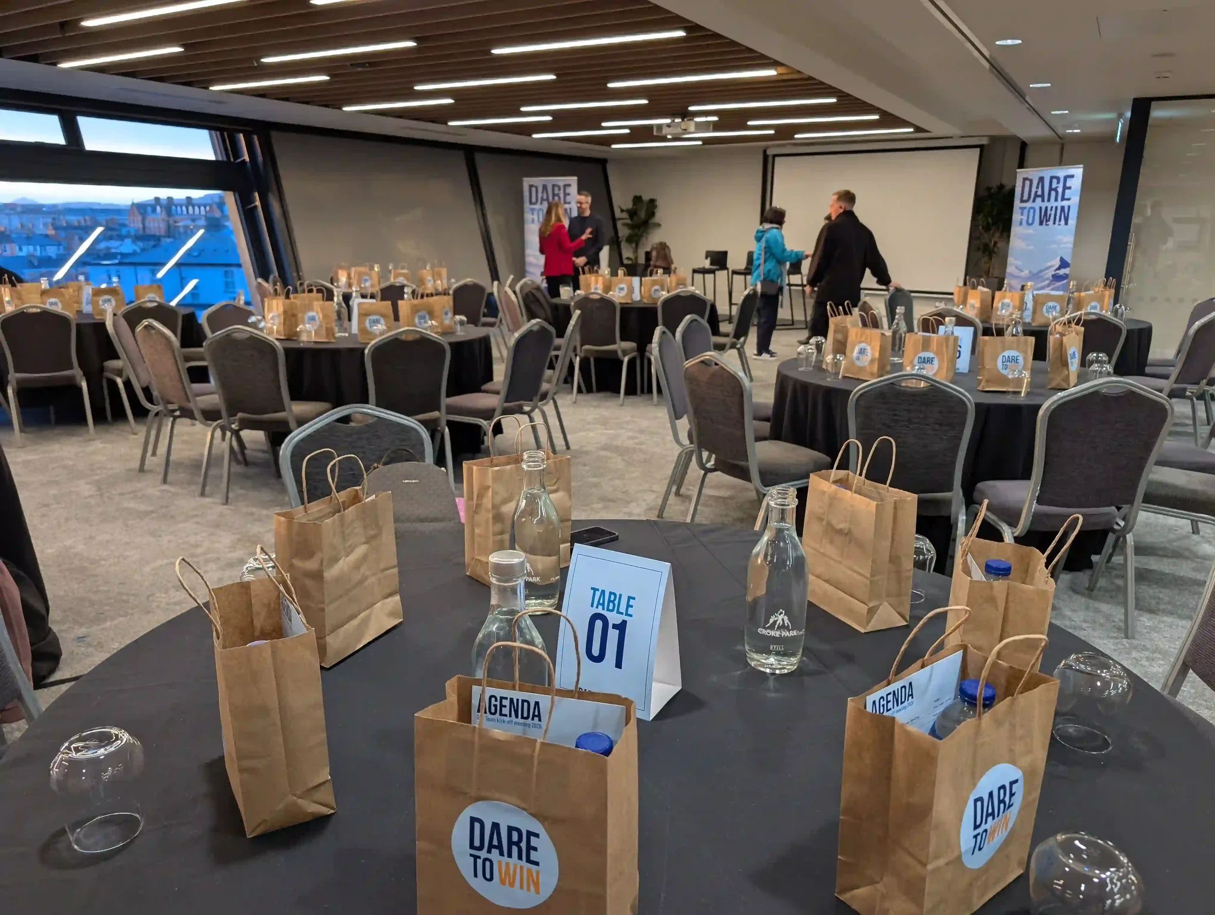 Corporate event room set up for Novo Nordisk's team kick-off meeting, showing branded table cards, goodie bags and Dare to Win roller banners across all touchpoints