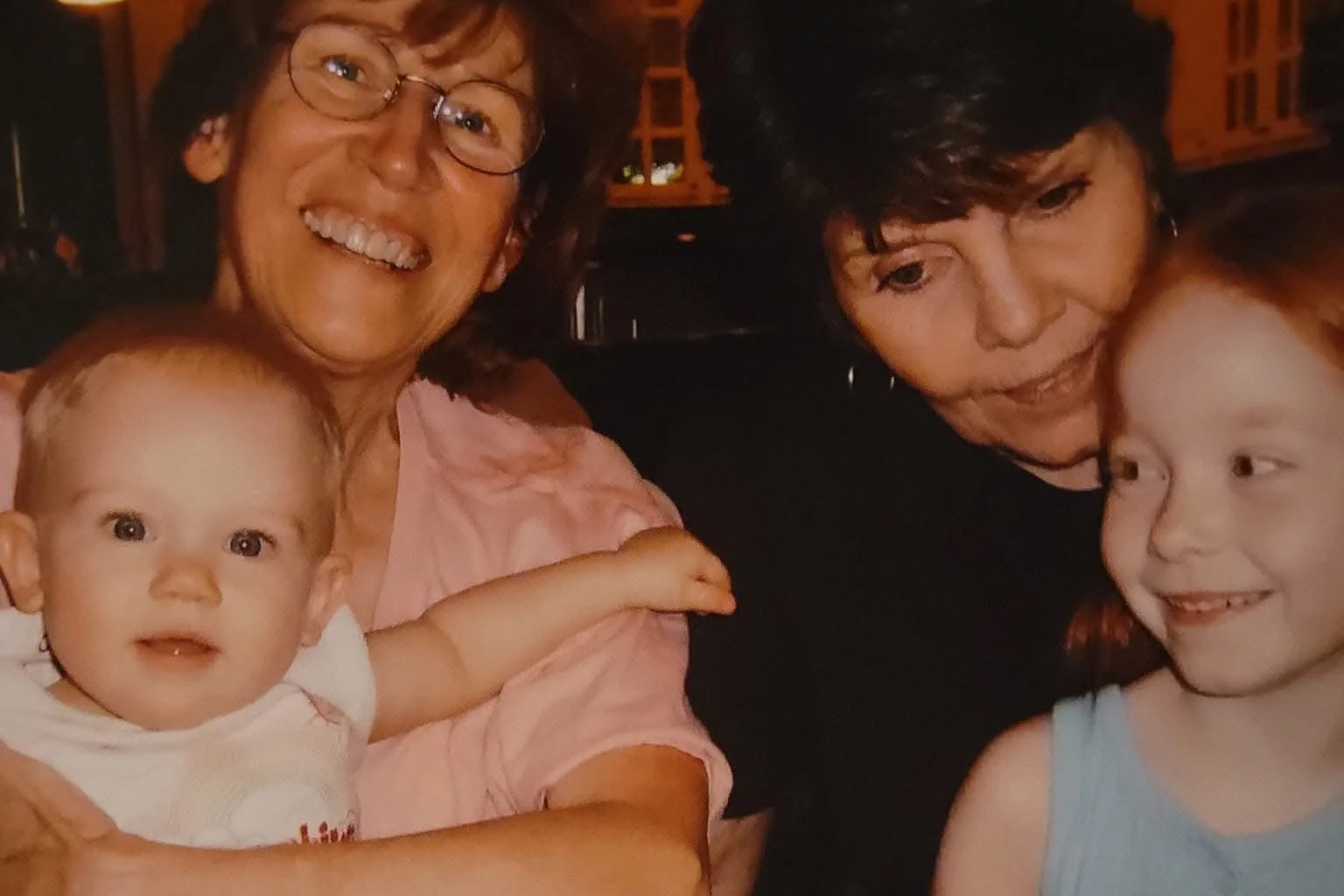 Four people, two children and two adults, smiling and enjoying time together in a dimly lit setting.