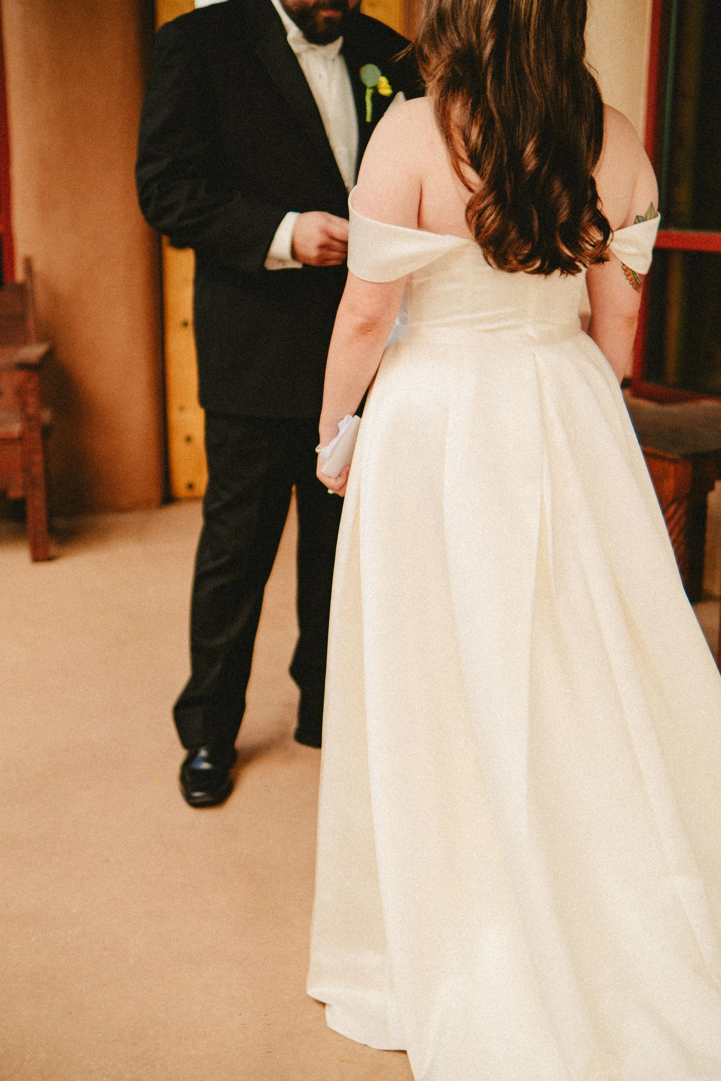 Bride and groom embracing during their New Mexico wedding. A bride in a white wedding dress standing in front of a man in a black tuxedo.