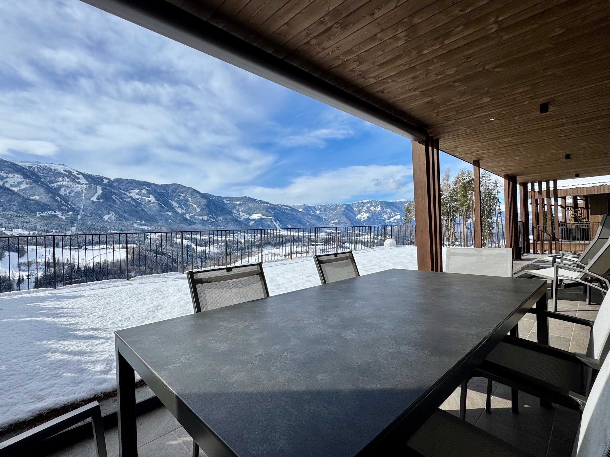 Überdachte Terrasse mit Esstisch und Bergblick, umgeben von Schnee und offener Winterlandschaft