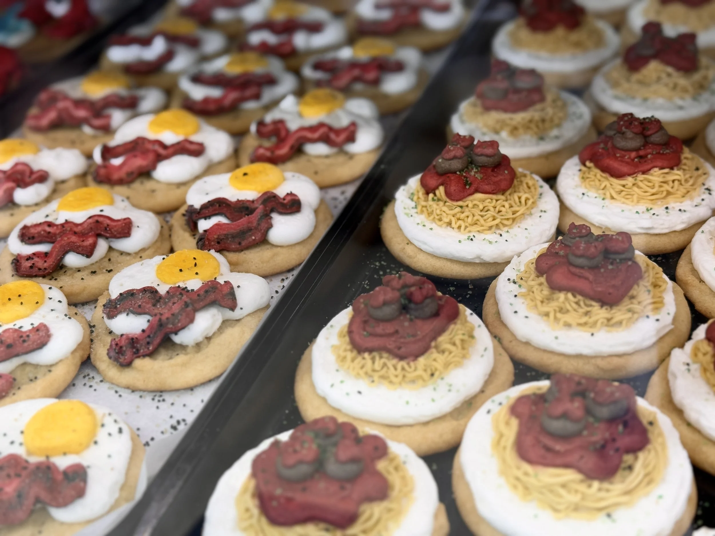 Tray of decorated cookies resembling fried eggs and ramen bowls.