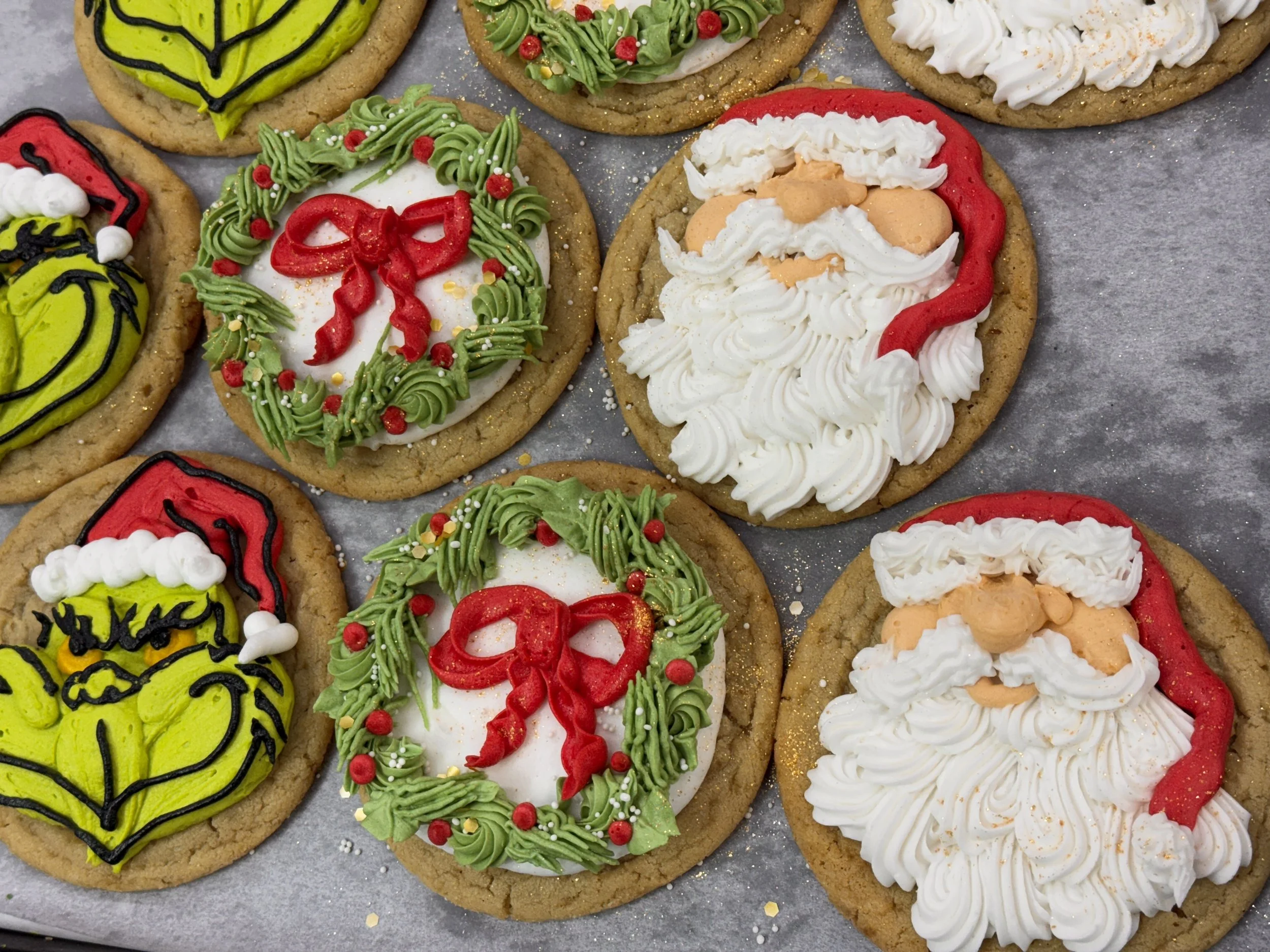 Assorted Christmas cookies decorated with green, red, white, and yellow icing and sprinkles, laid out on a gray surface.