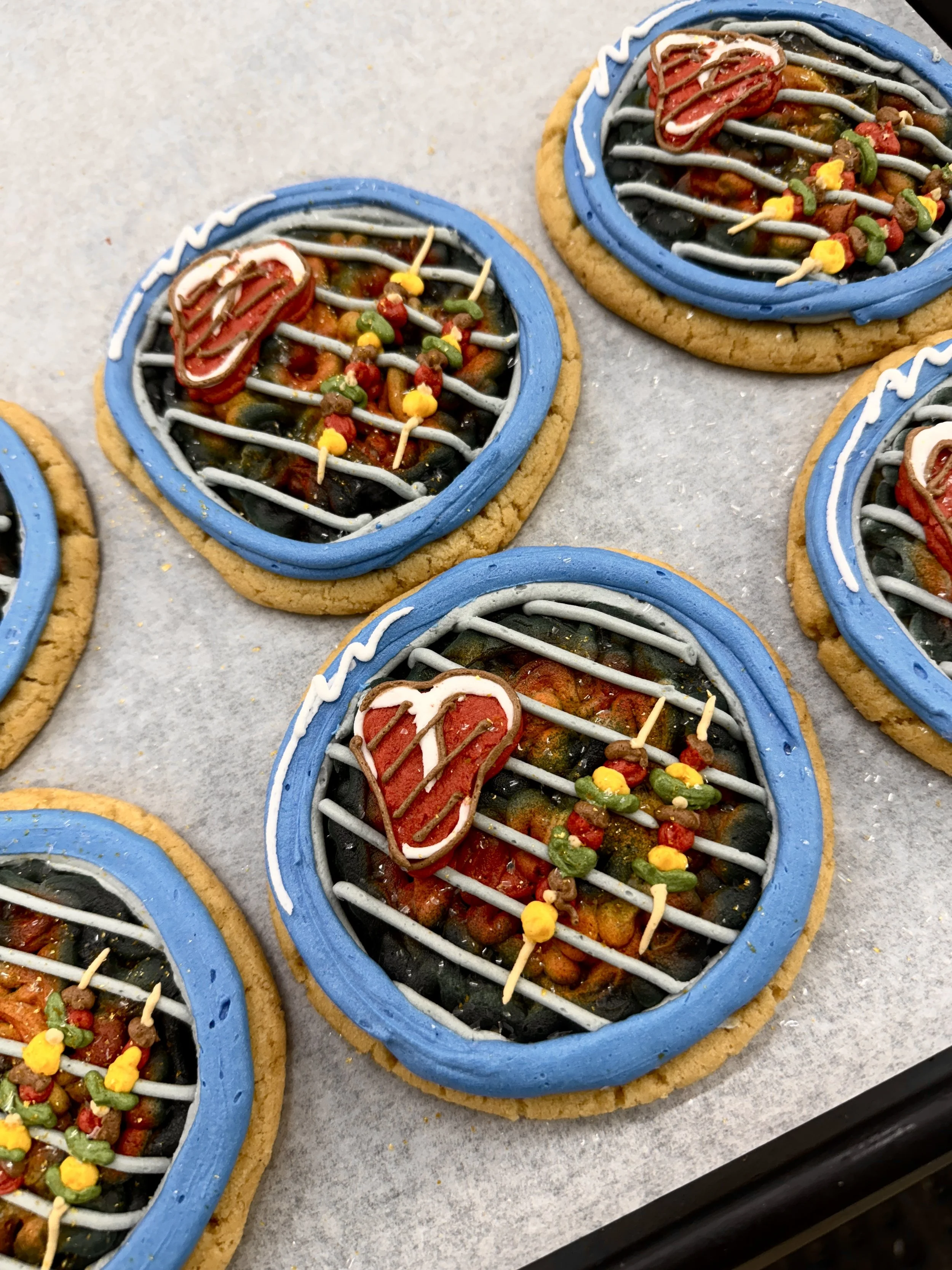 Cookies decorated to look like over-easy fried eggs with blue borders, red hearts, and colorful sprinkles, placed on a baking sheet.