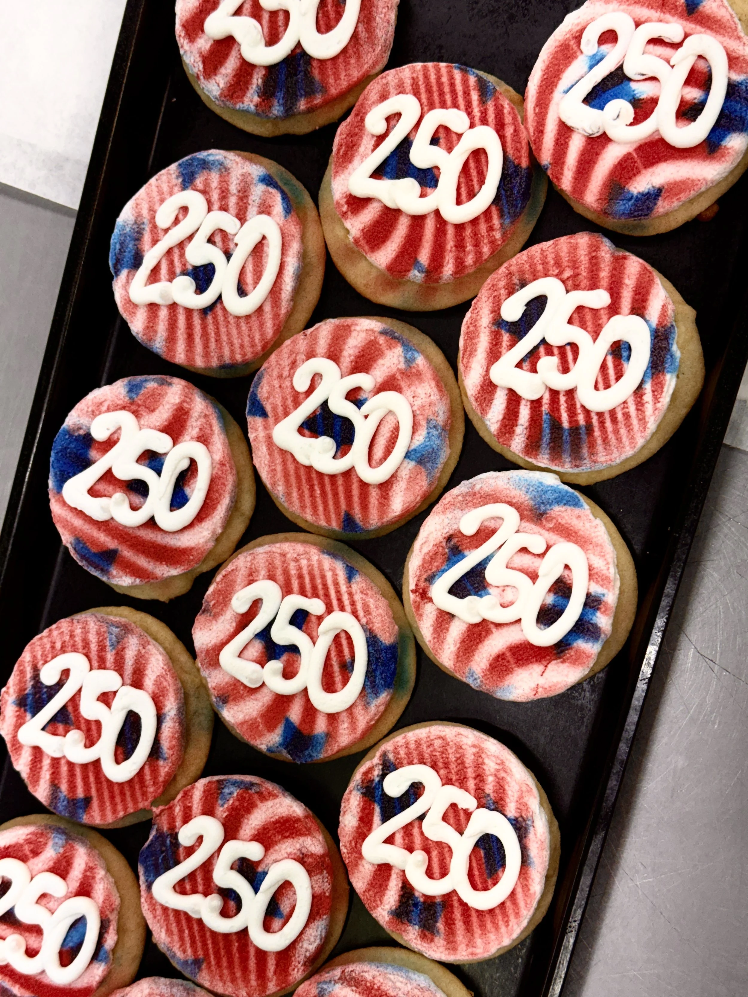 Cookies decorated with red, white, and blue icing, each with the number '250' written in icing on top.