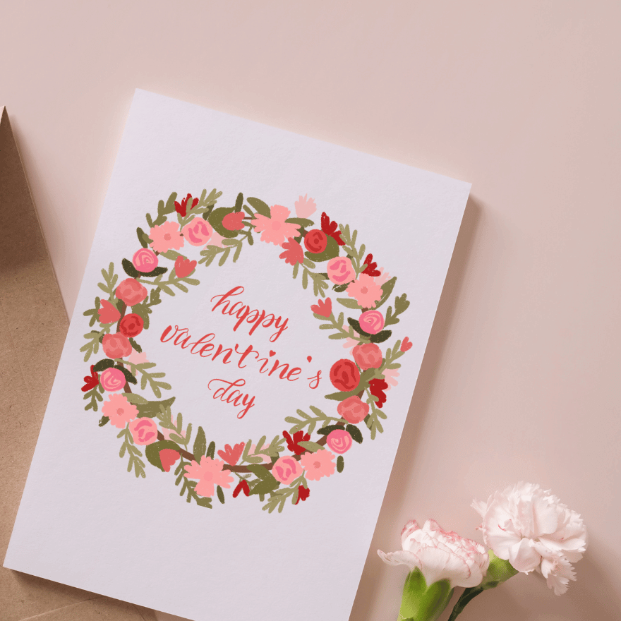 Hand lettering holiday card with pink and red floral wreath