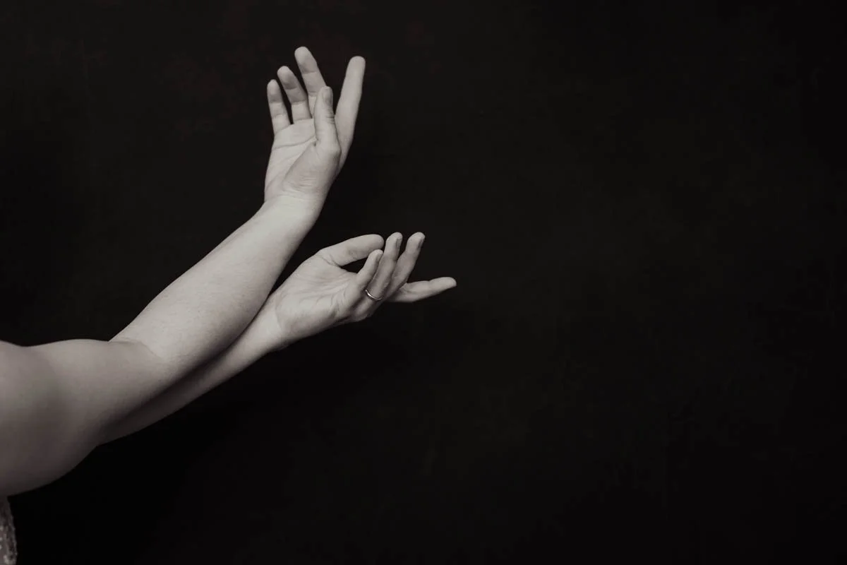 Two hands with fingers slightly bent, positioned against a black background.
