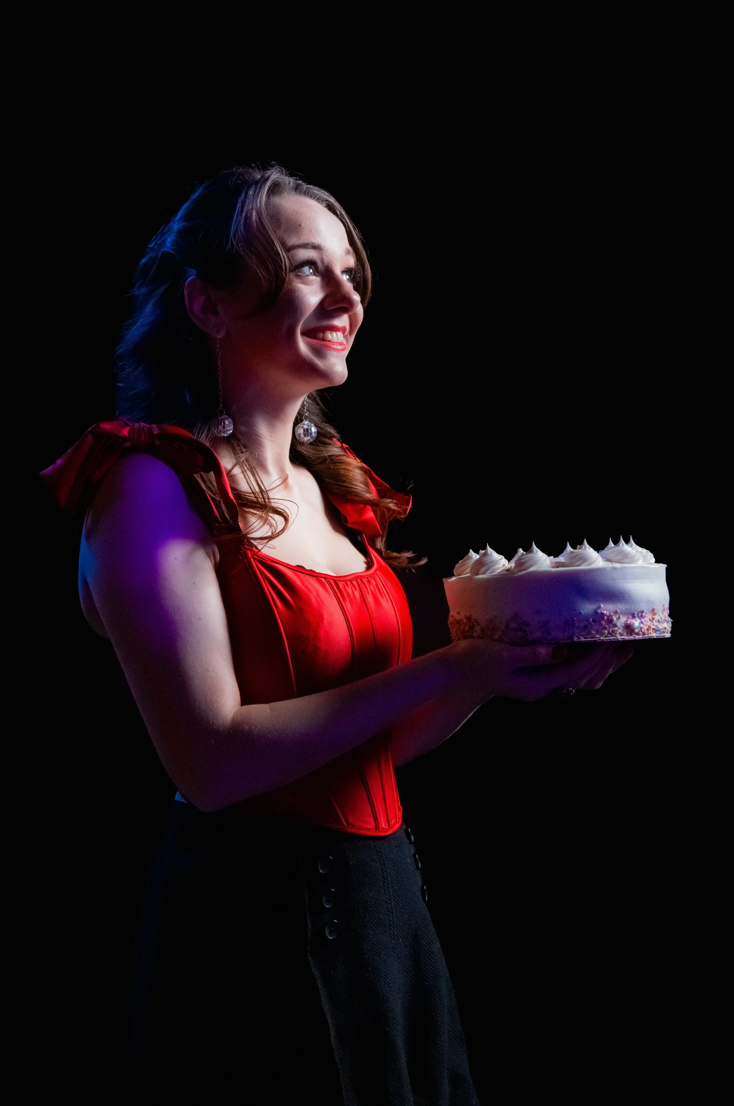 Woman in red dress holding a cake on stage