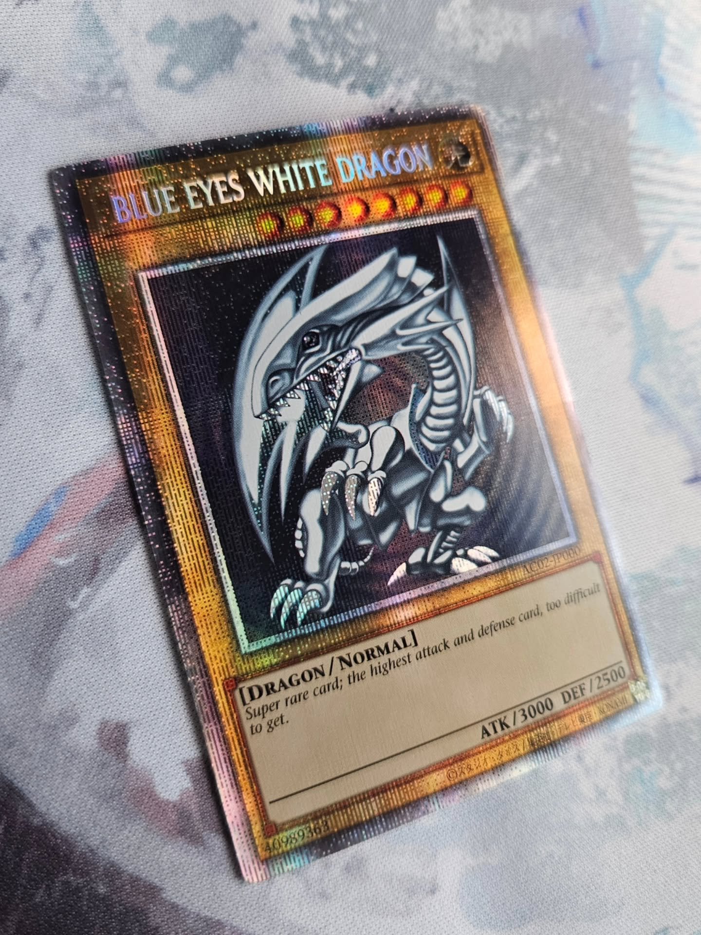 Super rare card; the highest attack and defense card, too difficult to get.

This is the unique flavor text on the AC02 Blue-Eyes White Dragon, which comes with the unusual "all caps" card name as well. This card, being an OCG card, has bee