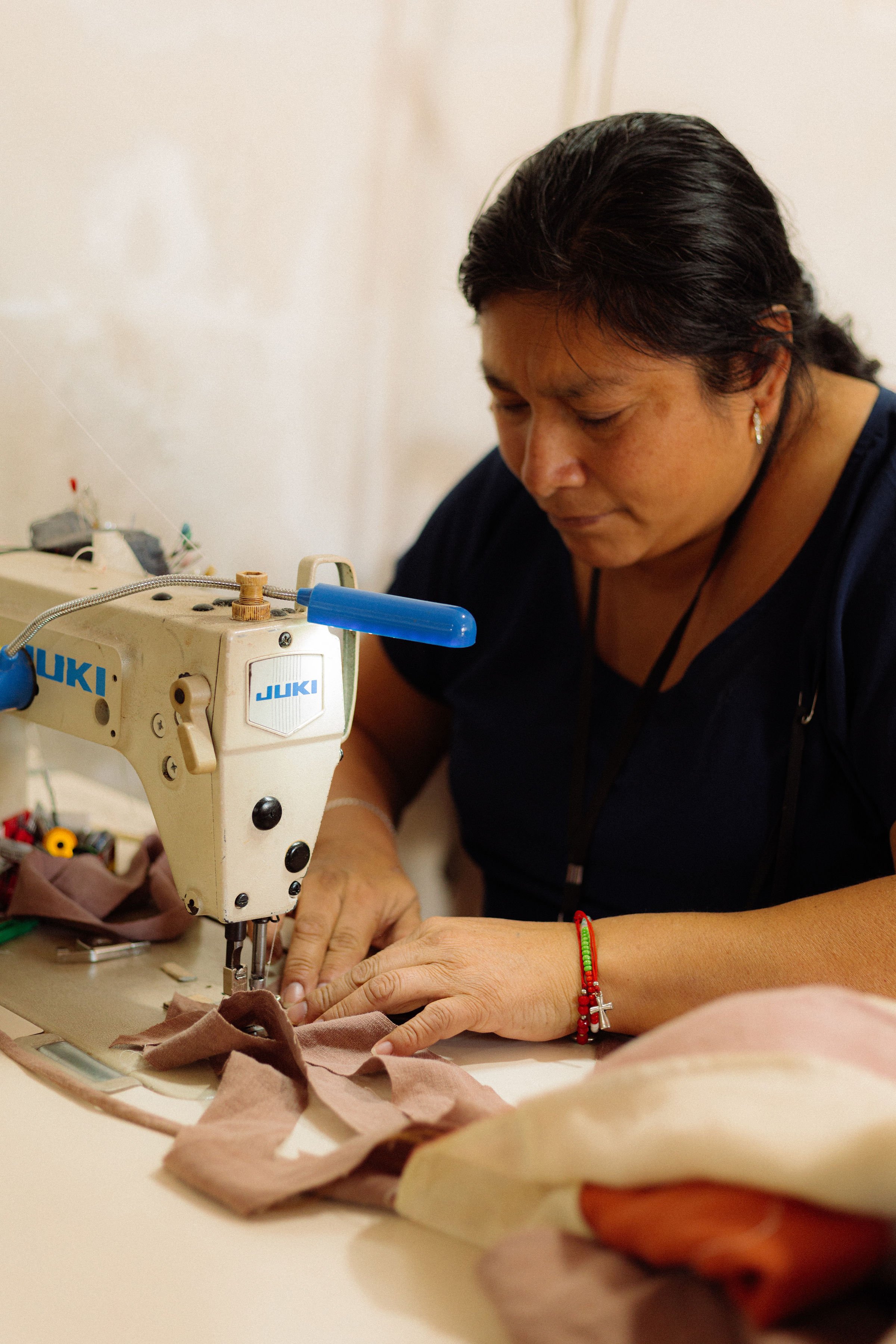 A woman working on a sewing machine focusing on sewing fabric.