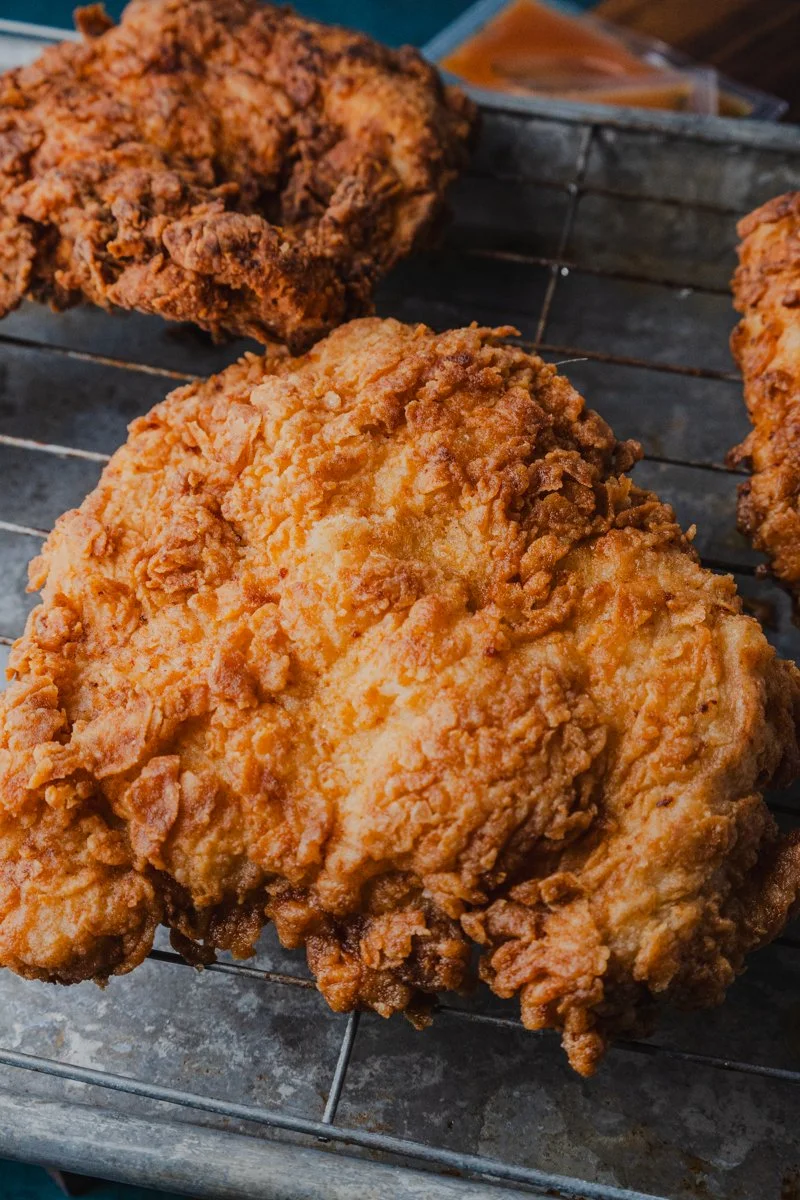 Process-focused food photography image of fried chicken resting on a rack, photographed as part of a personal project informing commercial food photography decisions
