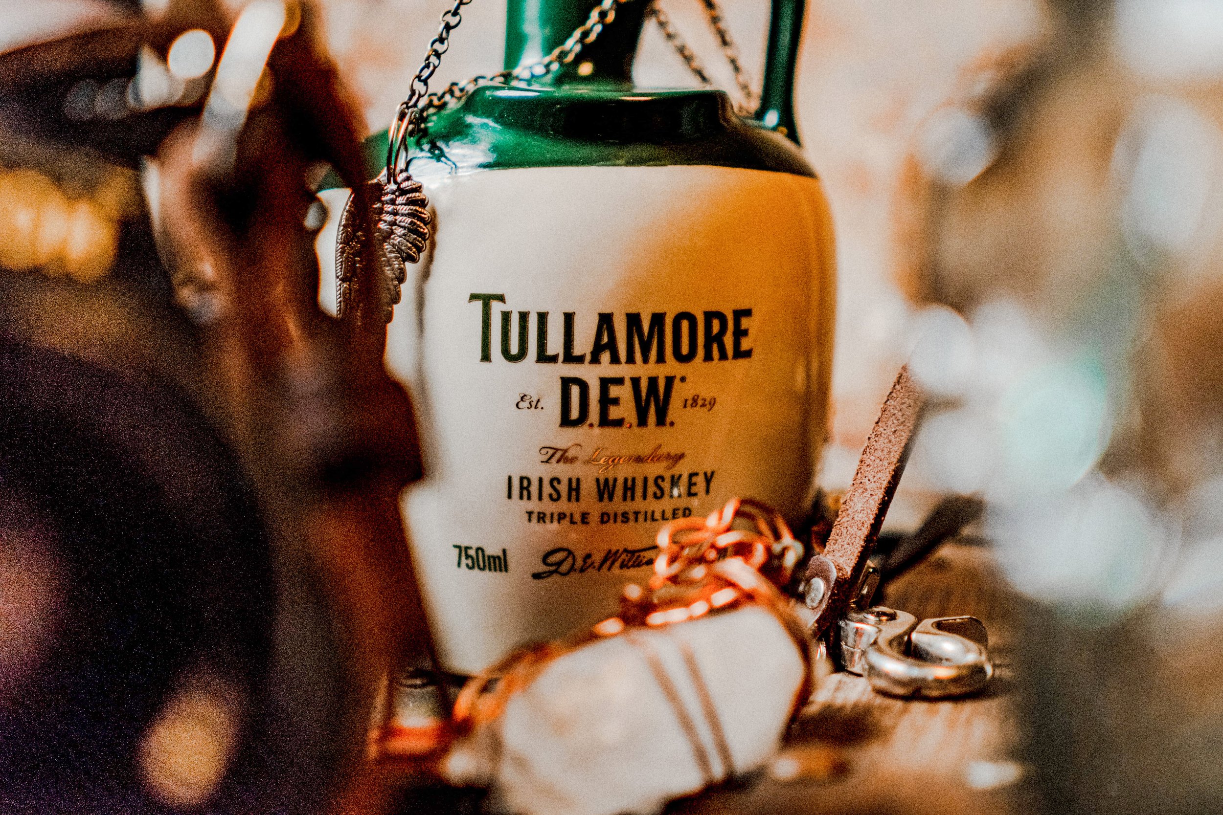 Tullamore D.E.W. Irish whiskey bottle photographed on a bar surface with accessories.